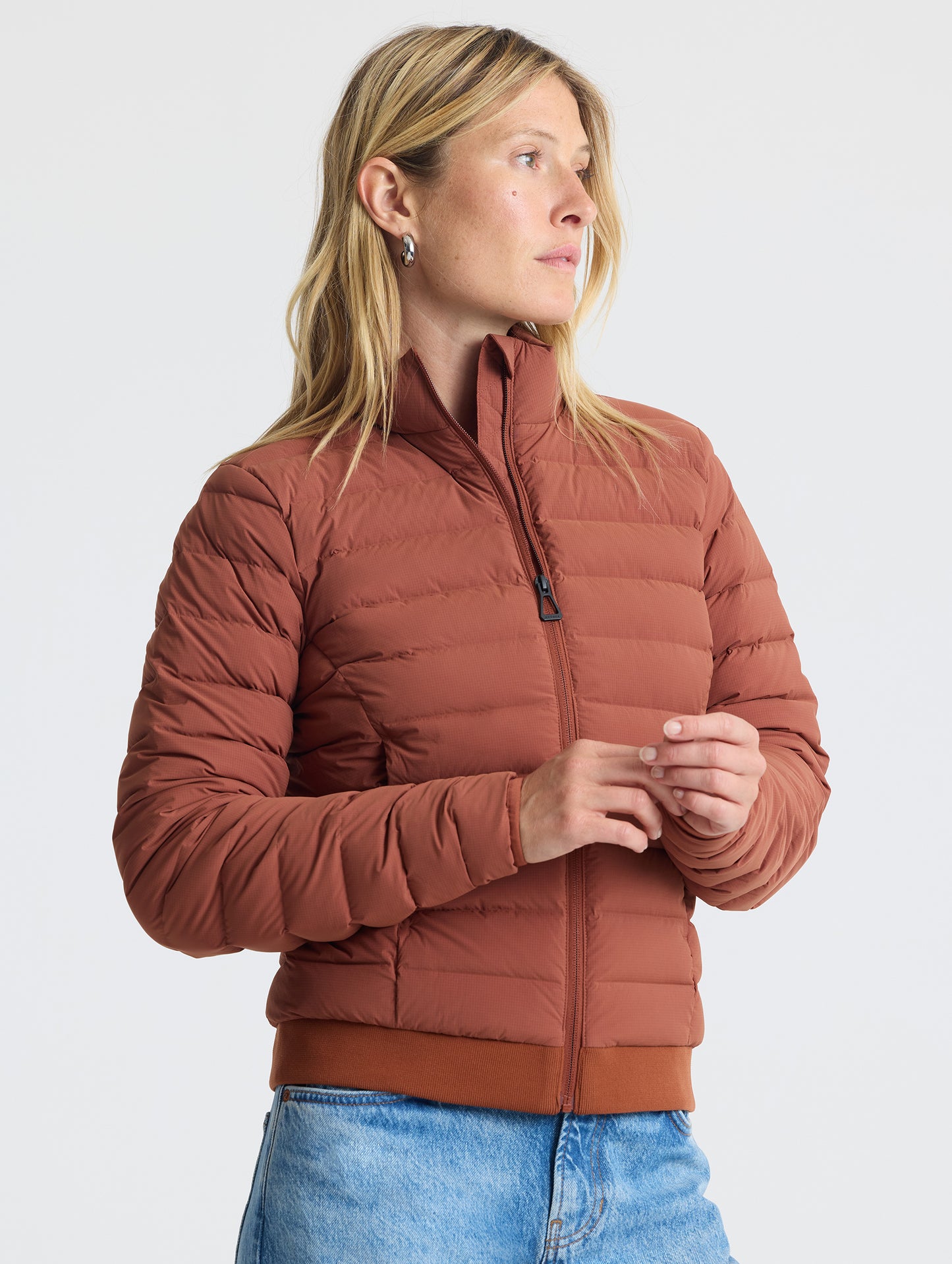 Angled view of woman wearing W Launch Full-Zip Jacket NH in Redwood Rust from AETHER Apparel.