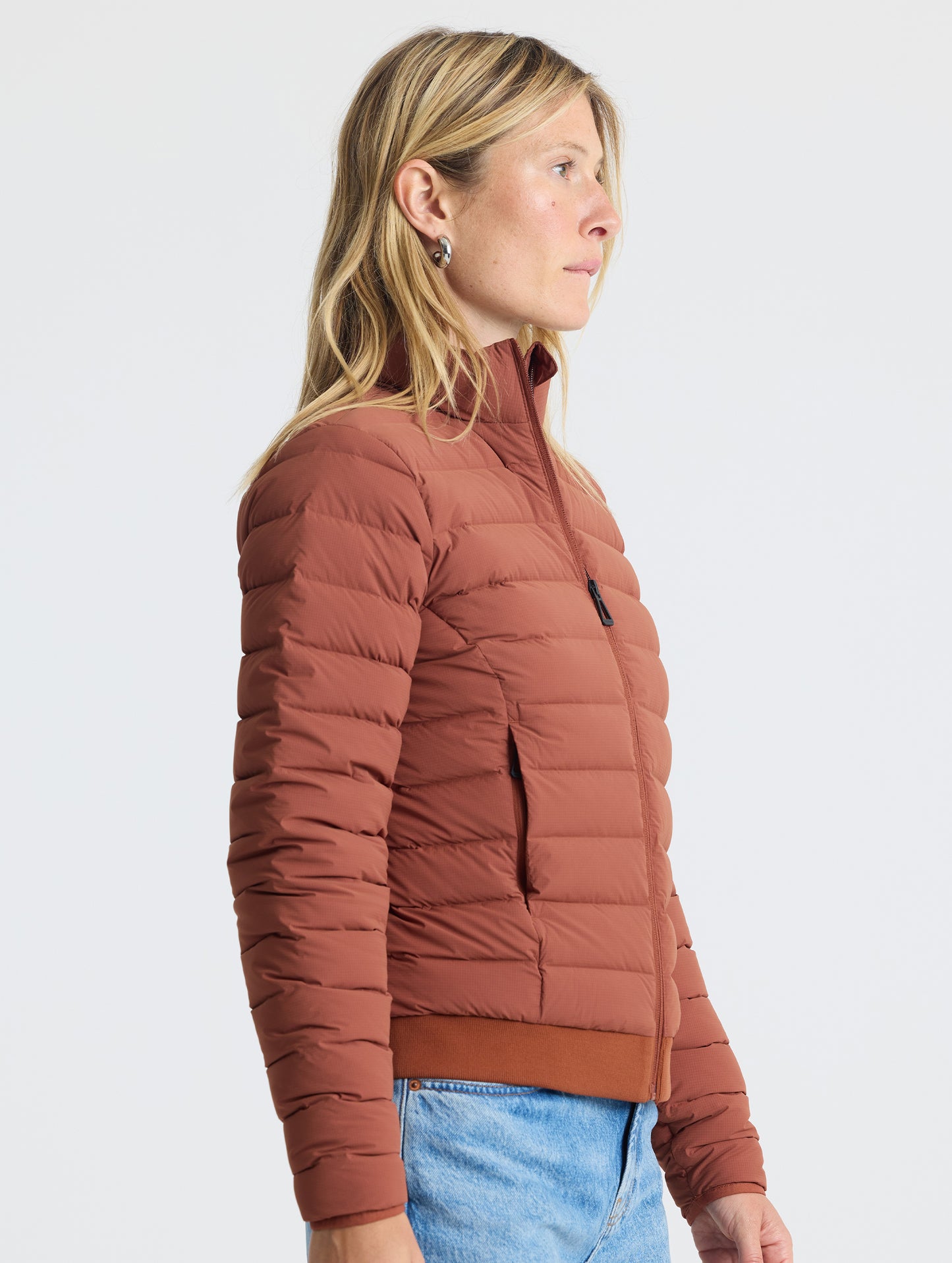 Right profile view of woman wearing W Launch Full-Zip Jacket NH in Redwood Rust from AETHER Apparel.