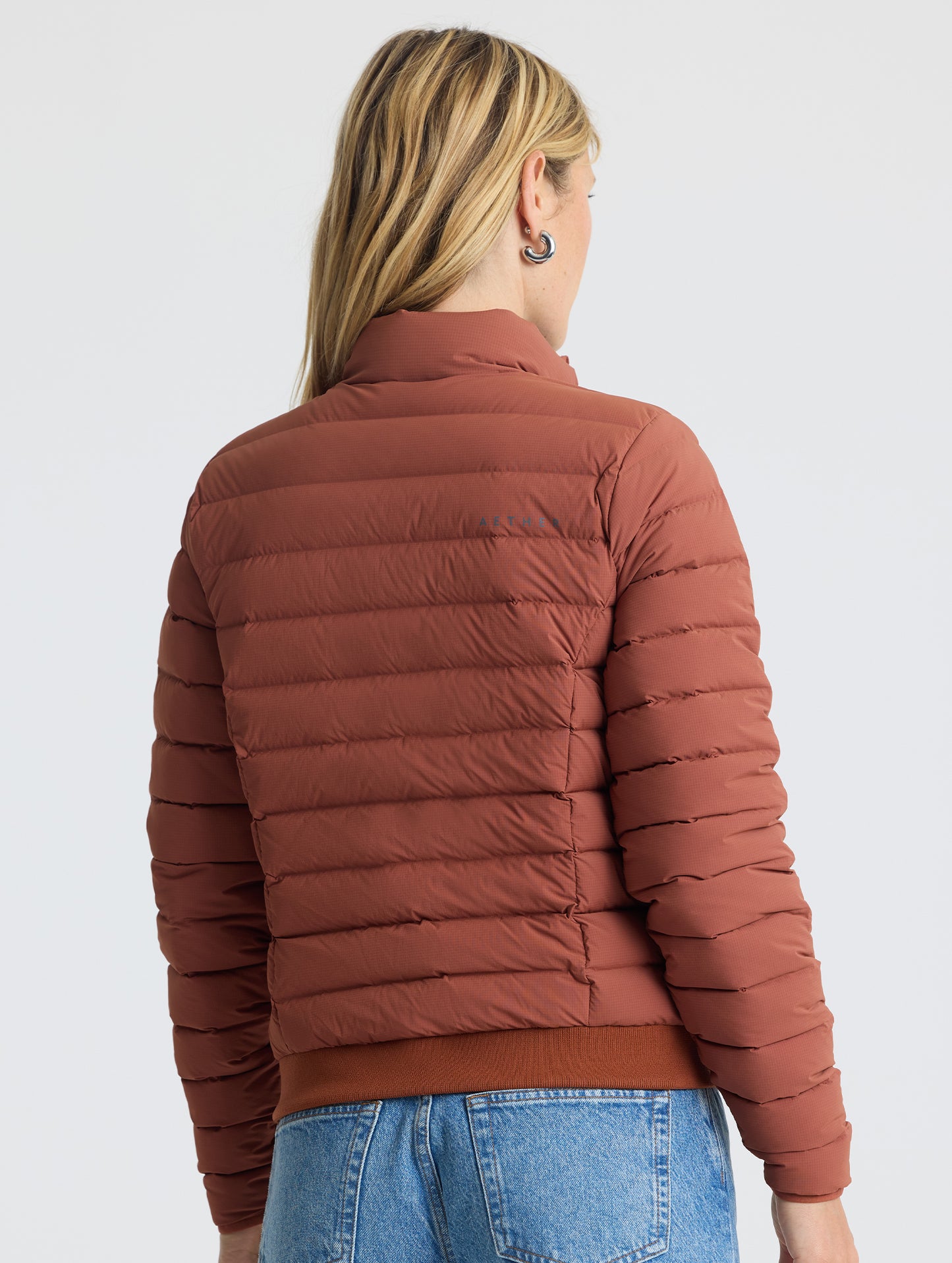 Rear view of woman wearing W Launch Full-Zip Jacket NH in Redwood Rust from AETHER Apparel.
