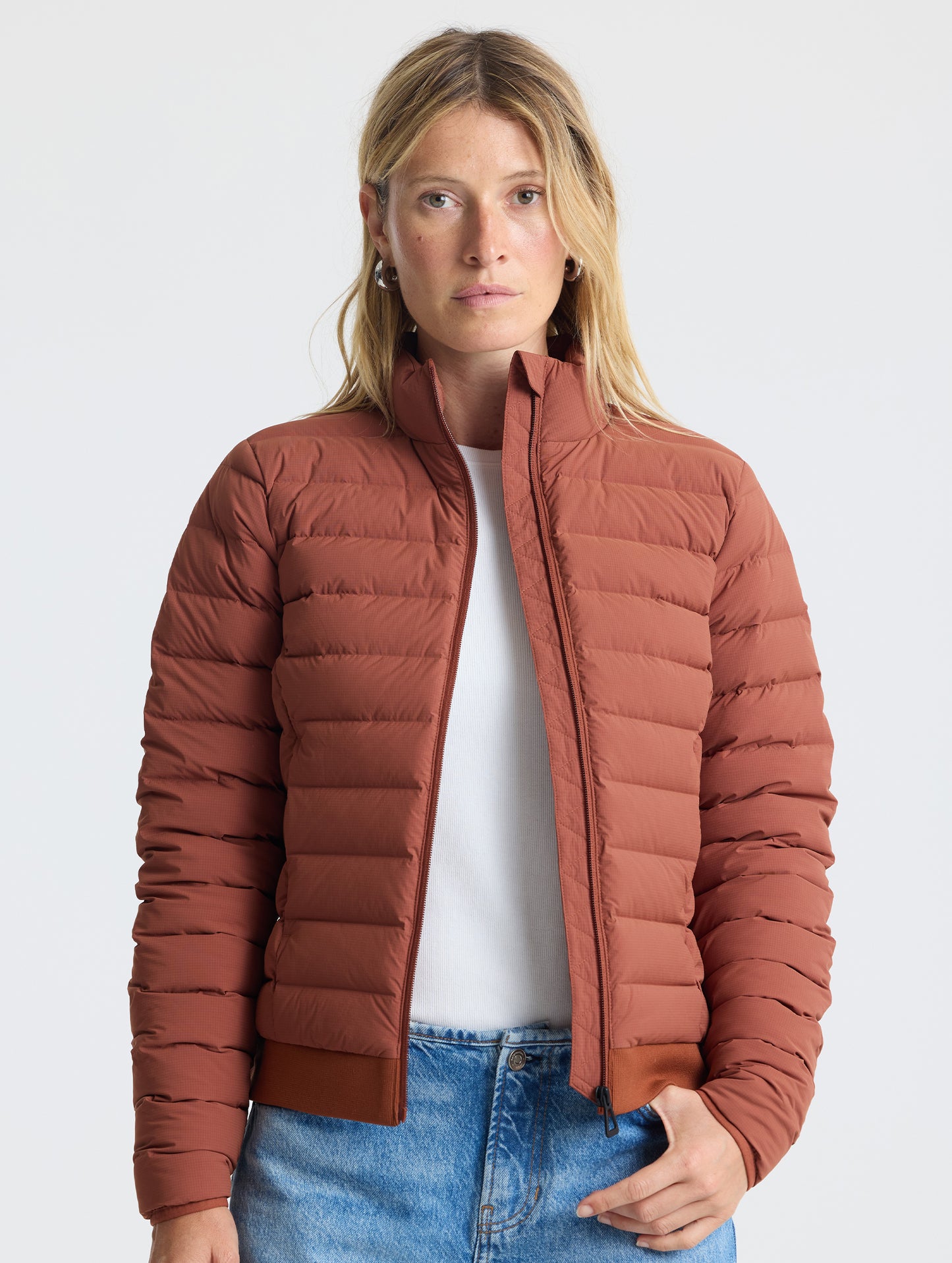 Front view of woman wearing unzipped W Launch Full-Zip Jacket NH in Redwood Rust from AETHER Apparel.