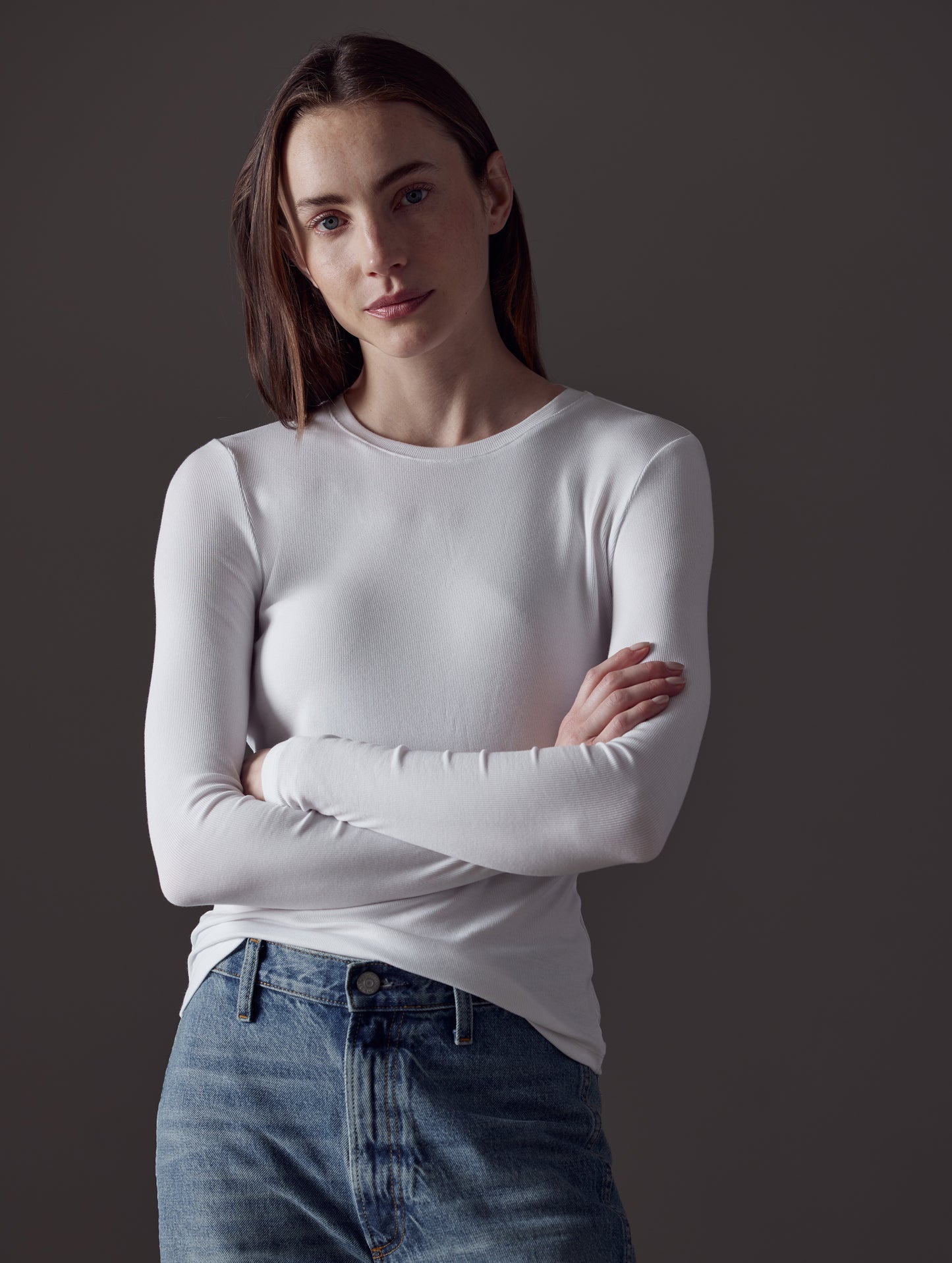 Front view of woman with arms crossed wearing Legacy Long-Sleeve Crew in White from AETHER Apparel.