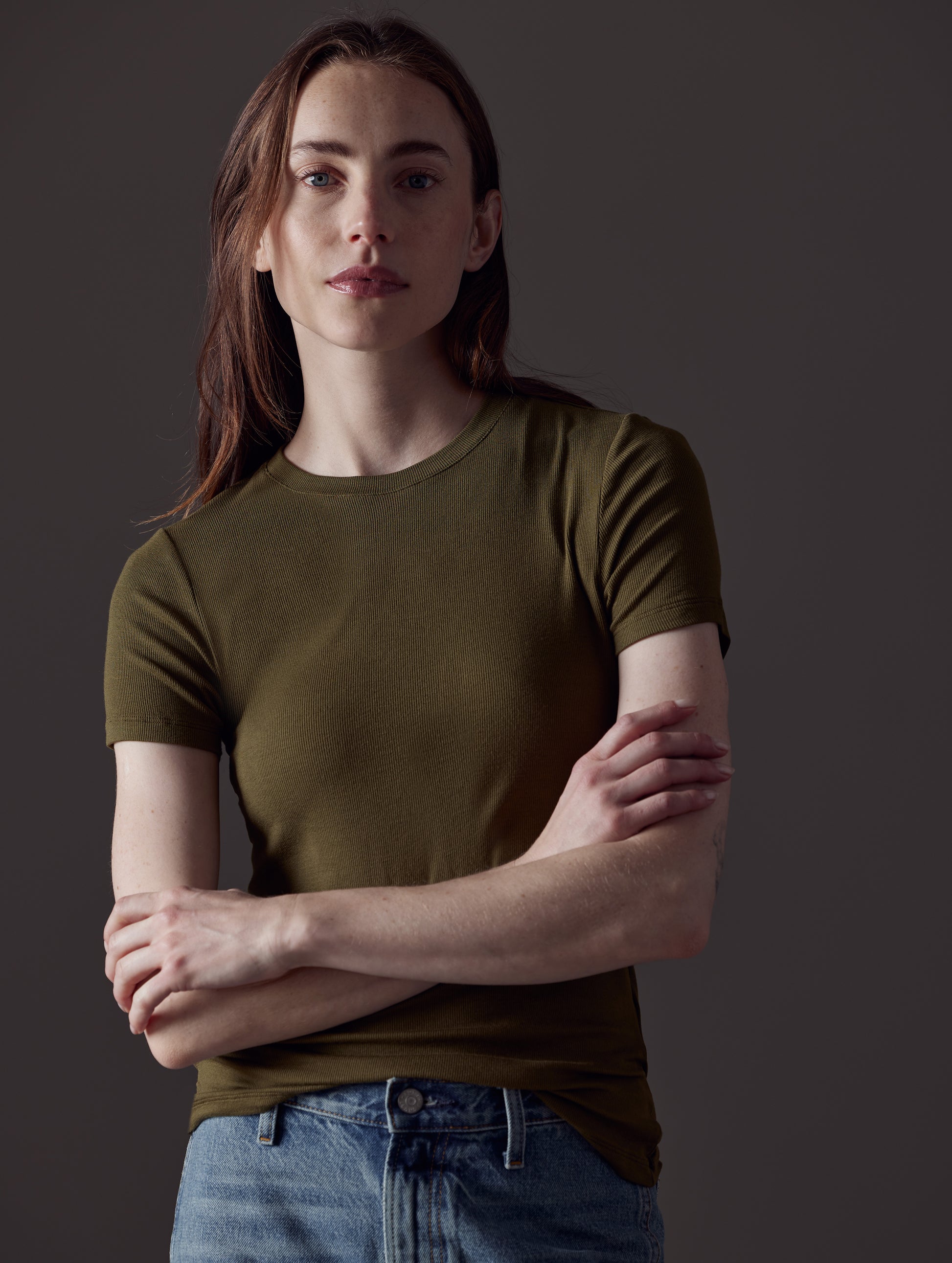 Front view of woman with arms crossed wearing Legacy Short-Sleeve Crew in Command Green from AETHER Apparel.