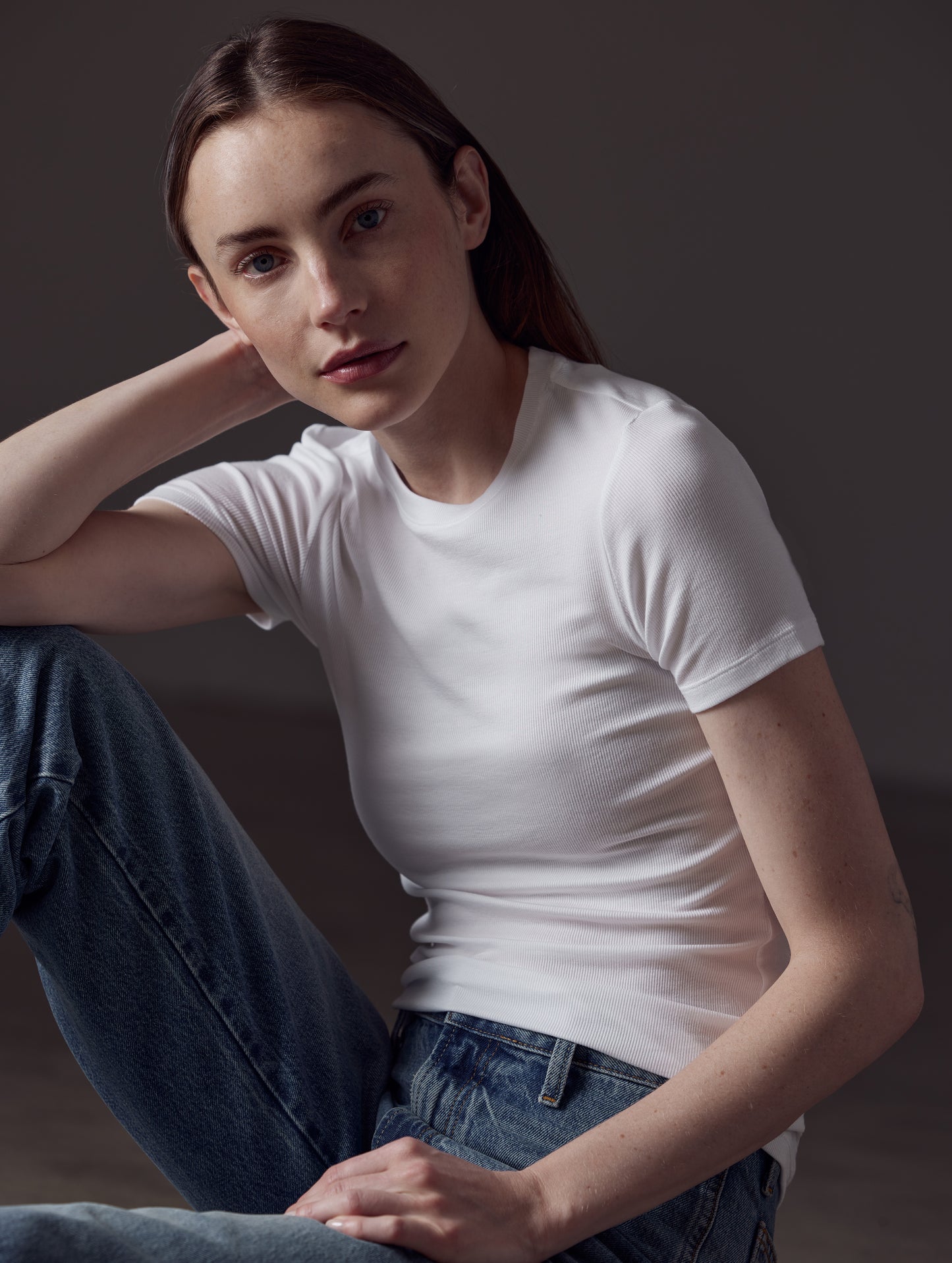 Closeup front angled view of woman sitting on floor wearing Legacy Short-Sleeve Crew in White from AETHER Apparel.