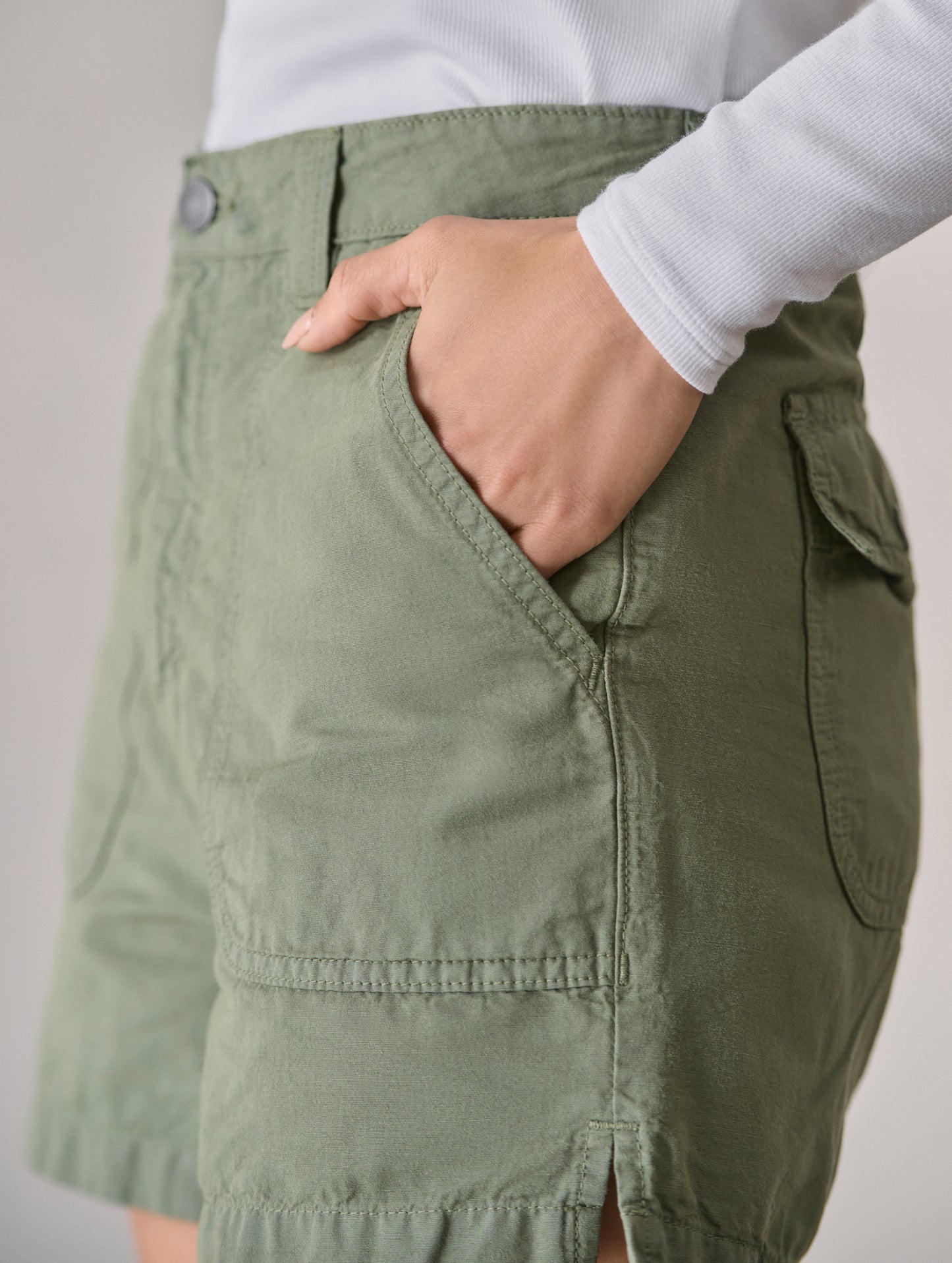 Closeup detailed view of woman with hand in rounded front patch pocket on the Masai Safari Short in Fern Green from AETHER Apparel.
