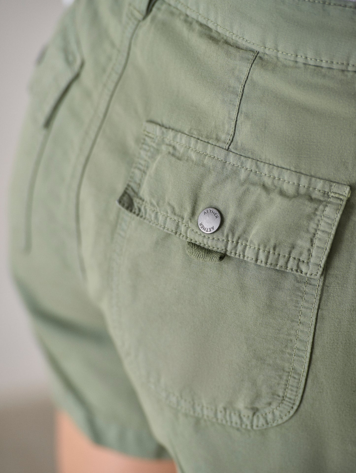 Closeup detail view of the snap-secured back patch pockets on the Masai Safari Short in Fern Green from AETHER Apparel.