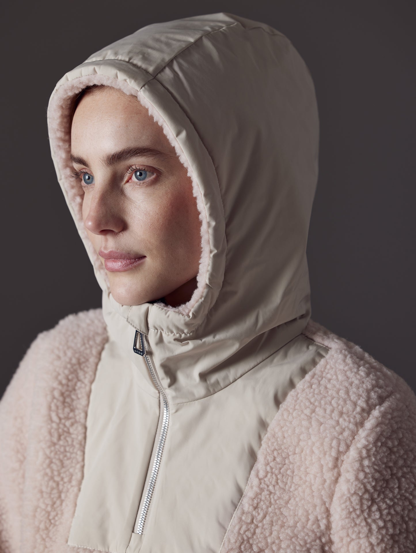 Close view of woman wearing pink Narrow Pullover from AETHER Apparel, displaying hood.