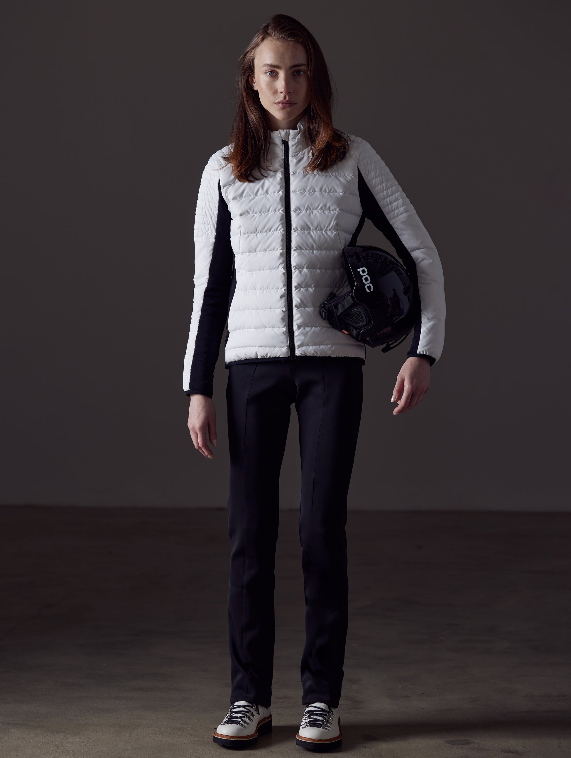 Front full-body view of woman holding helmet under arm wearing Ozone Jacket in White from AETHER Apparel.