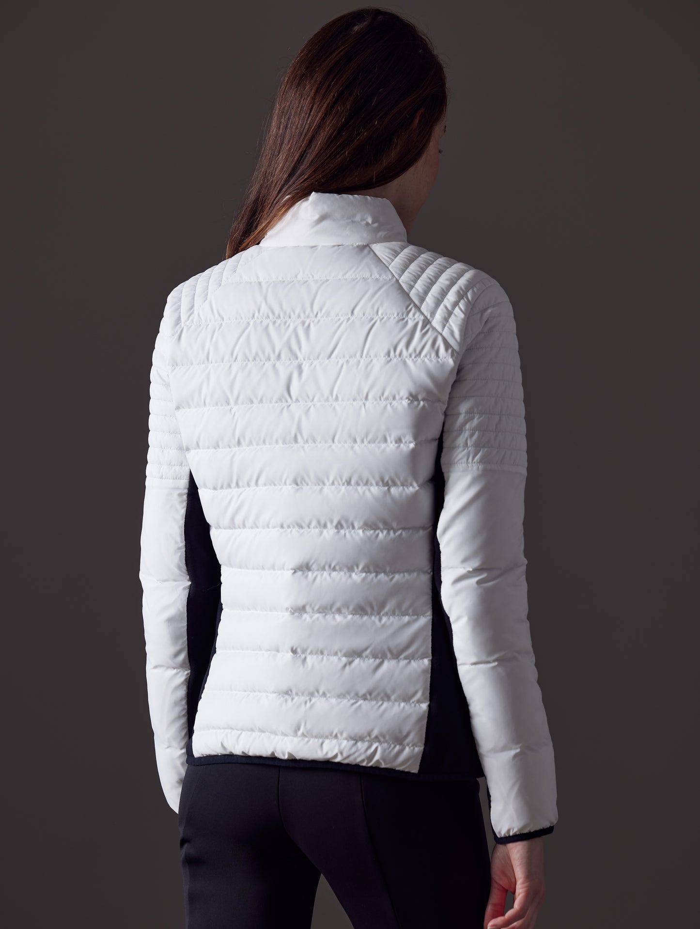 Rear angled view of woman wearing Ozone Jacket in White from AETHER Apparel.