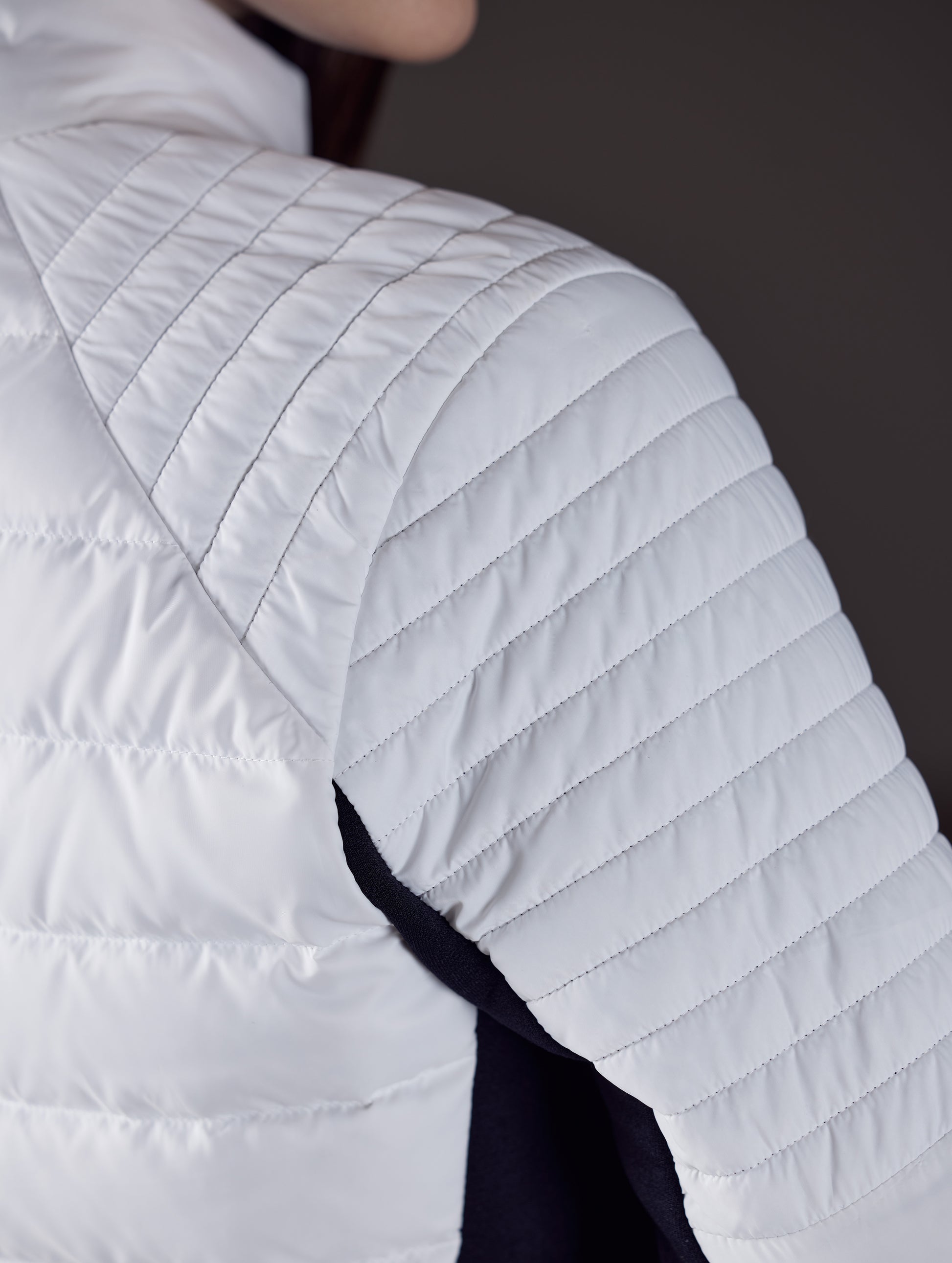 Closeup detailed view of quilted shoulder and baffling on women's Ozone Jacket in White from AETHER Apparel.