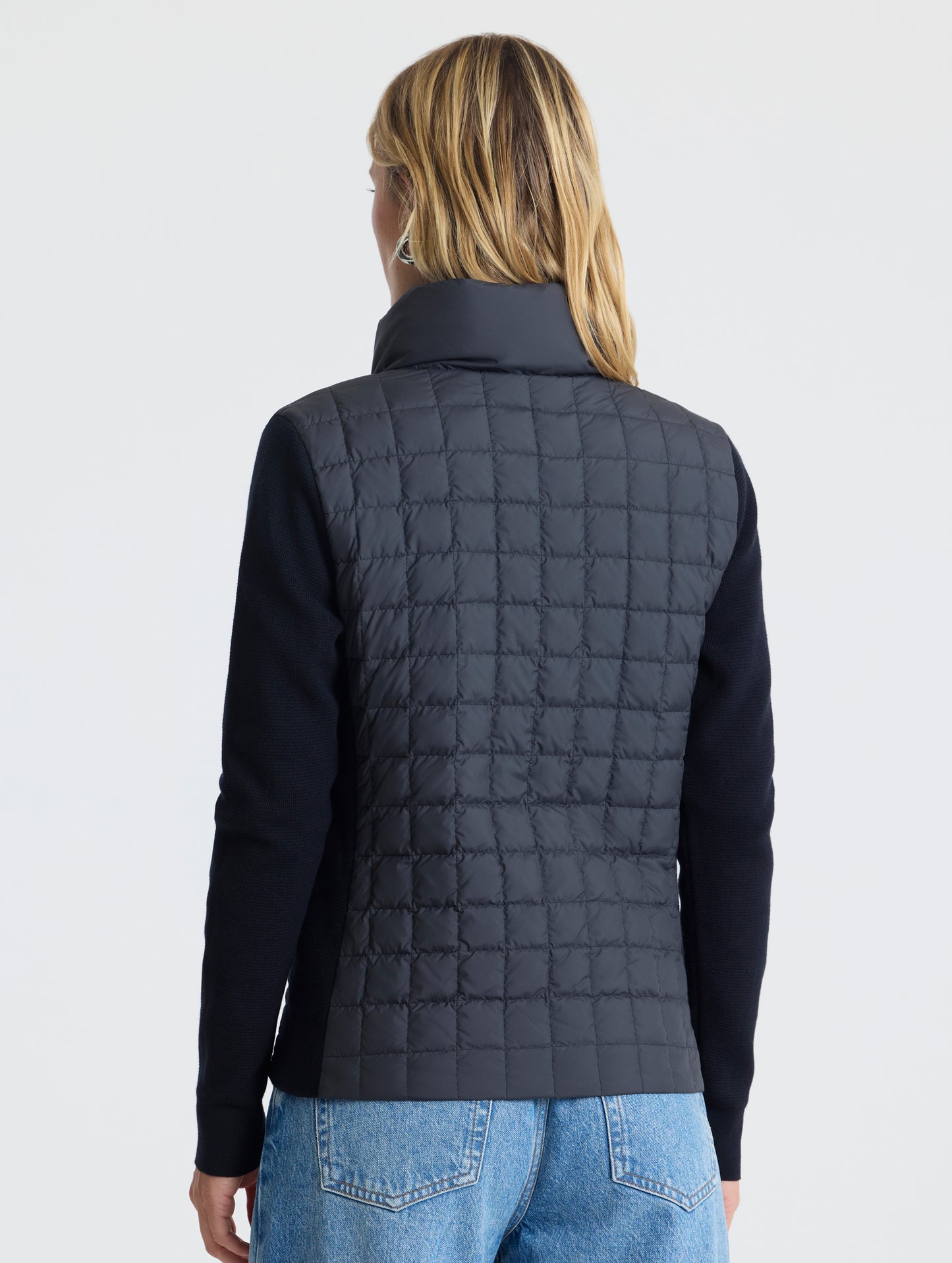 Rear, angled, upper-body view of woman wearing Phase Full-Zip in Onyx Black from AETHER Apparel.