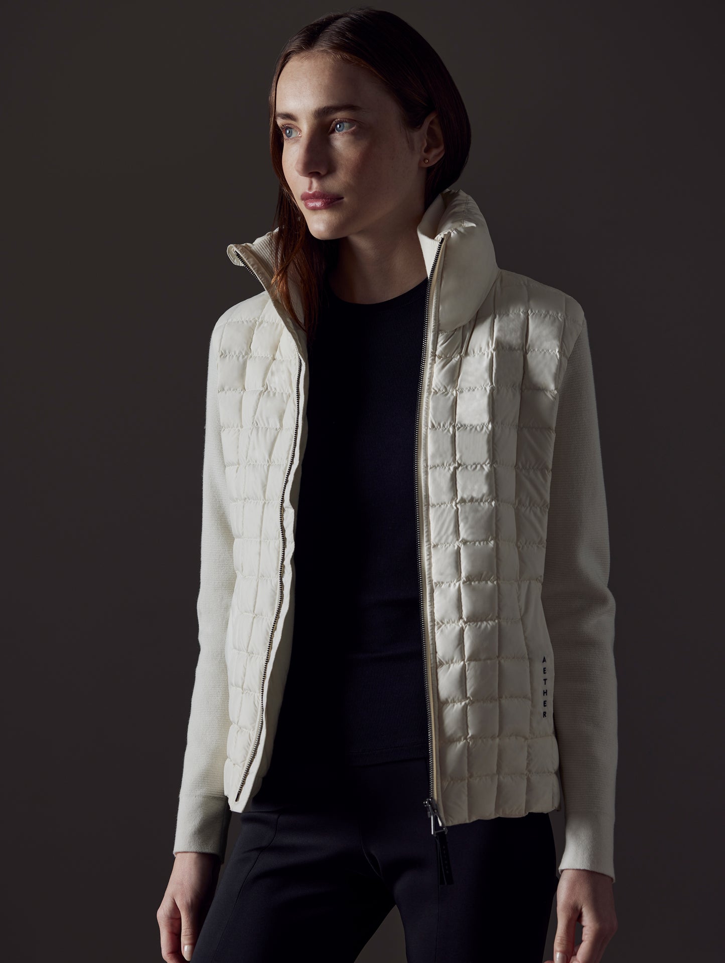 Front angled view of woman wearing unzipped Phase Full-Zip in Winter White from AETHER Apparel.