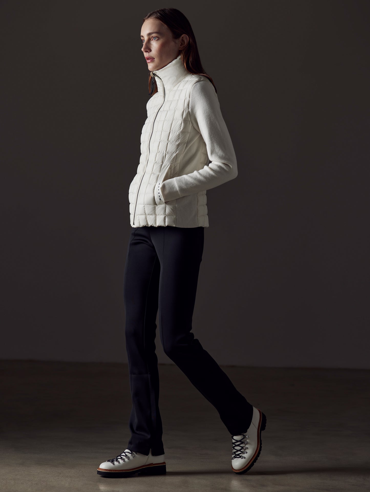 Side profile full-body view of woman wearing Phase Full-Zip in Winter White from AETHER Apparel.