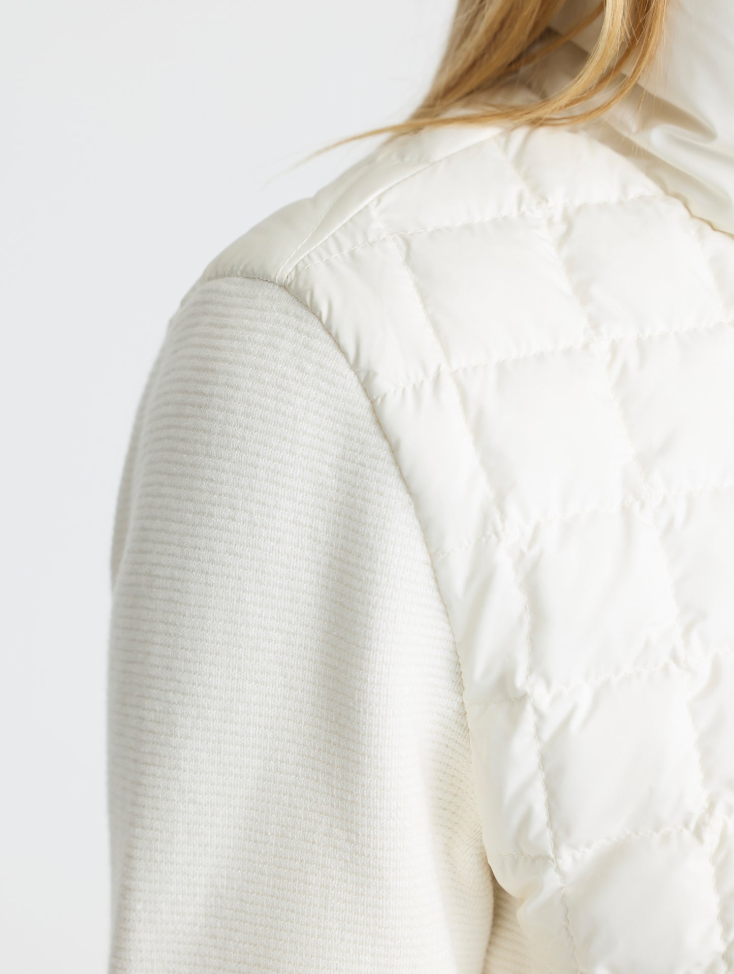 Closeup detailed view of the hybrid water-resistant woven shell fabric body and cotton-cashmere blend sleeves on the Phase Full-Zip in Winter White from AETHER Apparel.