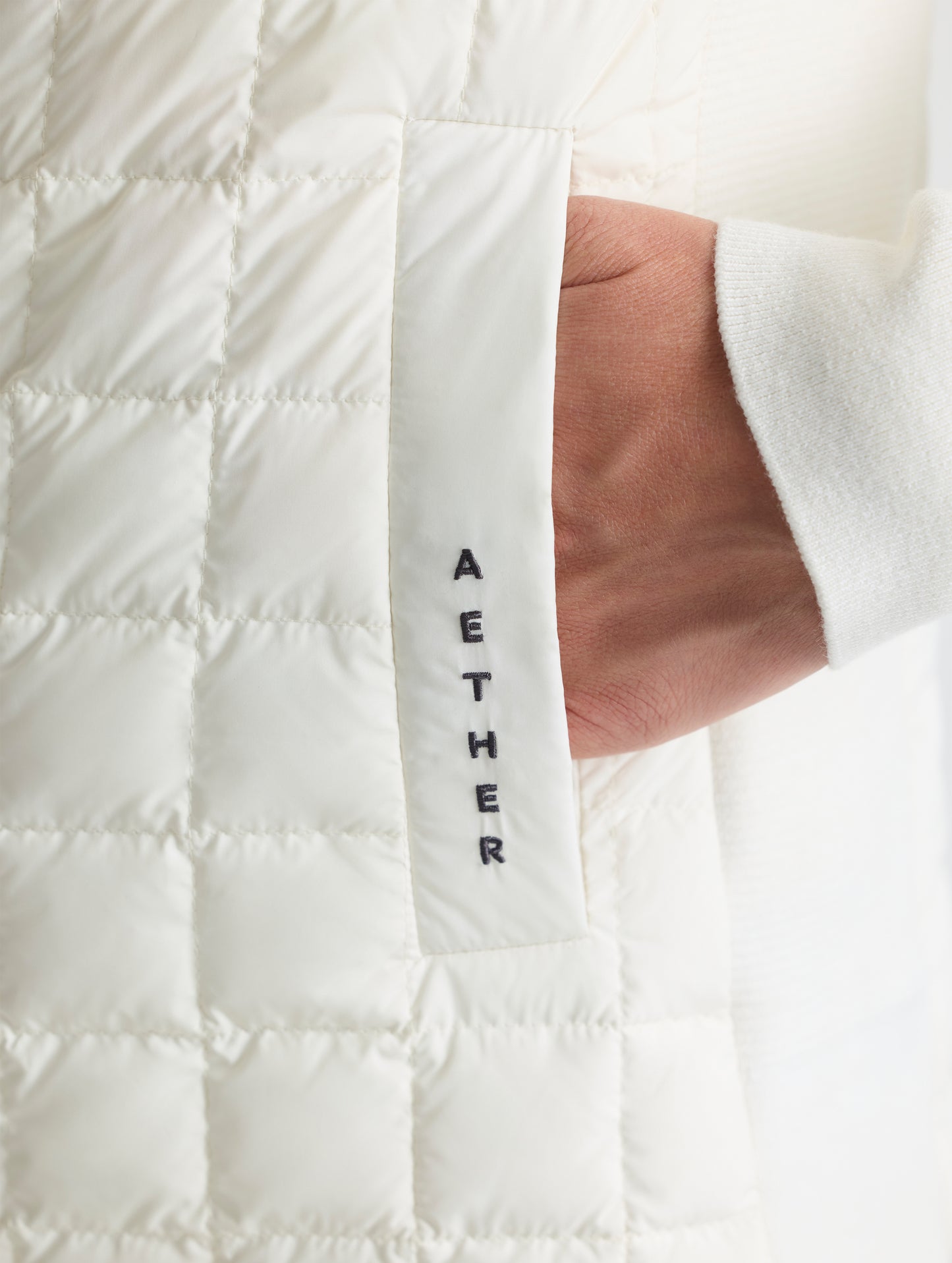 Closeup detailed view of the welt hand pocket on the Phase Full-Zip in Winter White from AETHER Apparel.