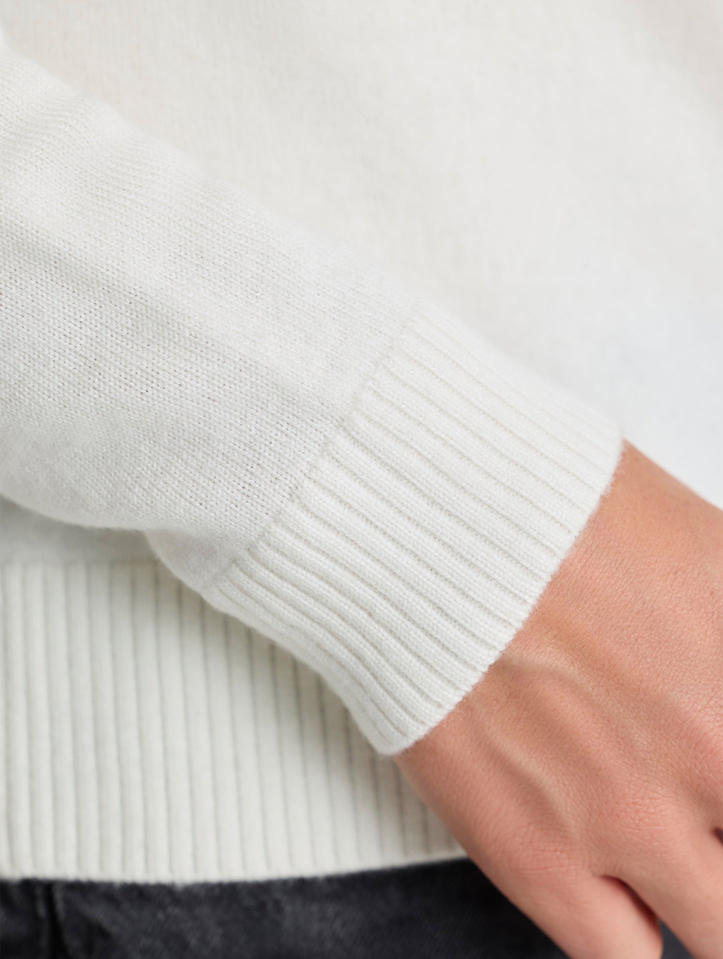 Closeup view of sleeve opening of Racer Sweater 2.0 in Winter White from AETHER Apparel (product available in Onyx Black).