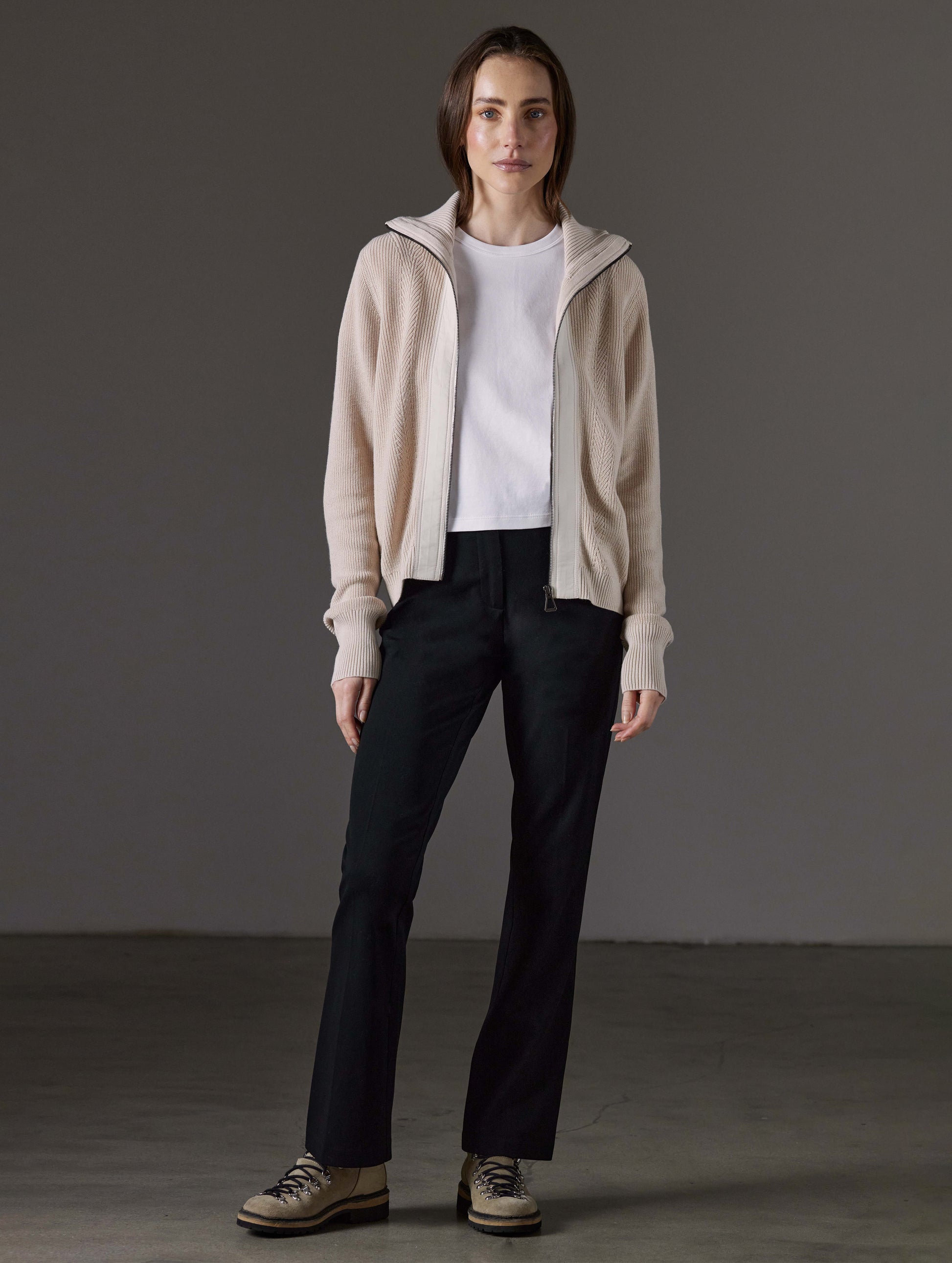 Front full-body view of woman wearing unzipped Rhea Full-Zip Sweater in Bone white from AETHER Apparel.