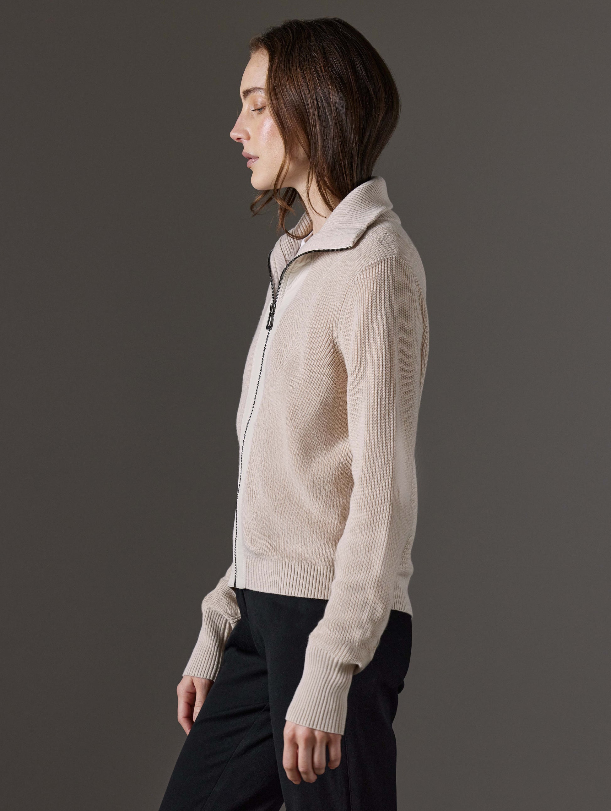 Side profile view of woman wearing Rhea Full-Zip Sweater in Bone white from AETHER Apparel.