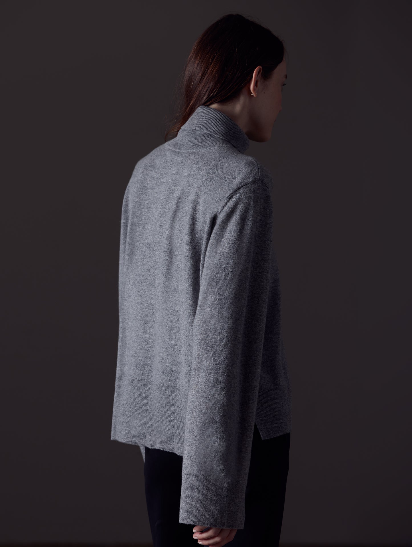 Rear angled view of woman wearing Leigh Cashmere Turtleneck Sweater in Heather Grey from AETHER Apparel.
