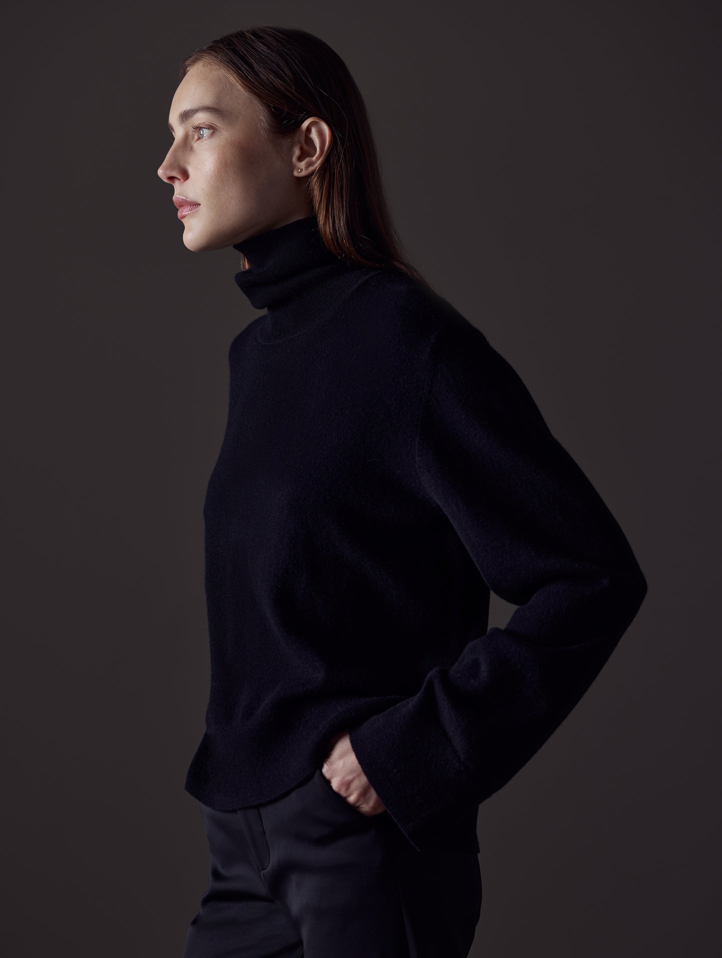 Side profile view of woman wearing Leigh Cashmere Turtleneck Sweater in Onyx Black from AETHER Apparel.