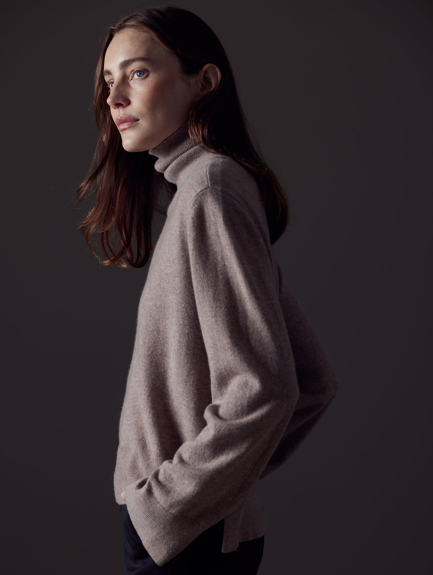 Side profile view of woman wearing Leigh Cashmere Turtleneck Sweater in Toast Brown from AETHER Apparel.
