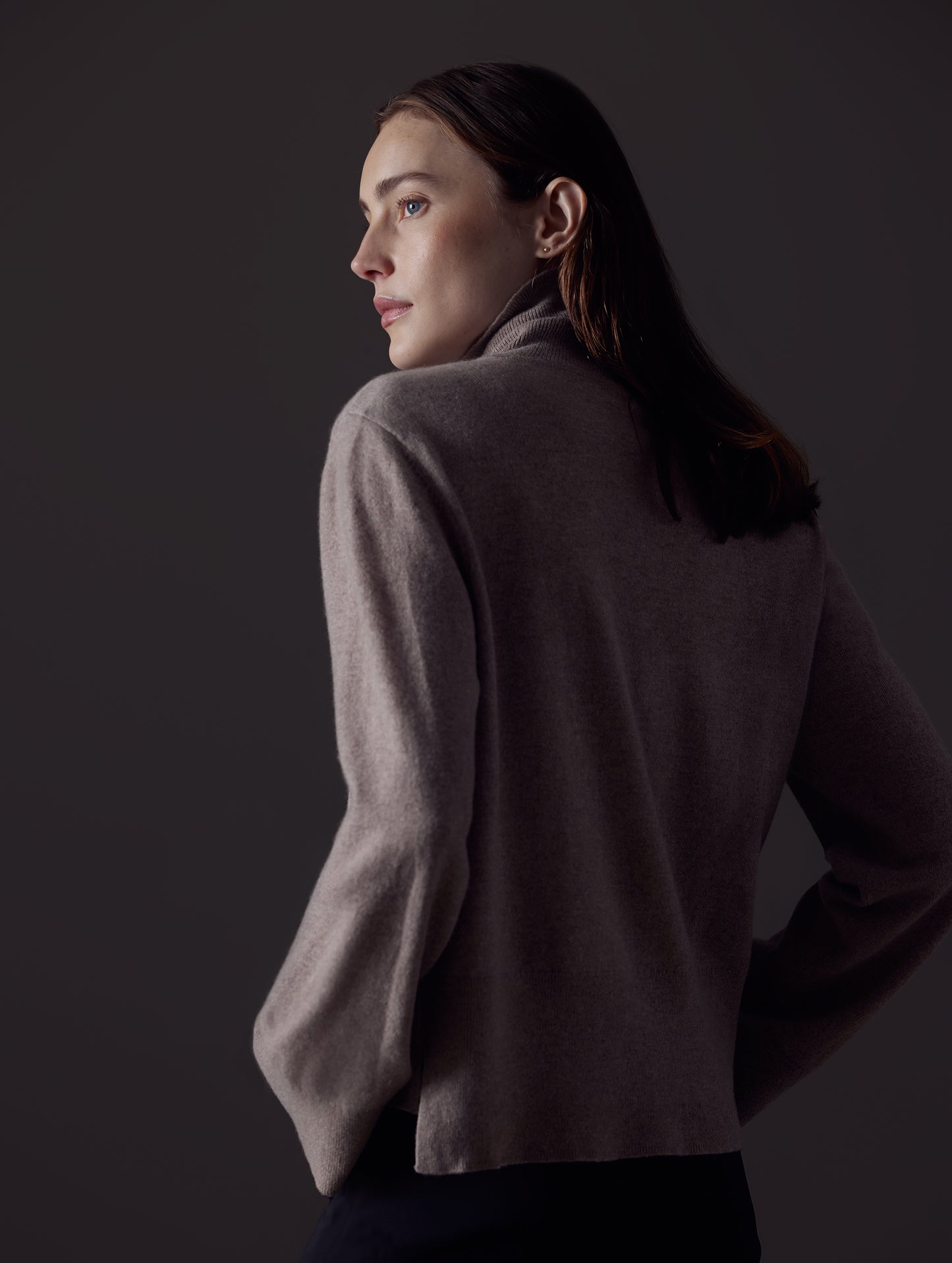 Rear angled view of woman wearing Leigh Cashmere Turtleneck Sweater in Toast Brown from AETHER Apparel.