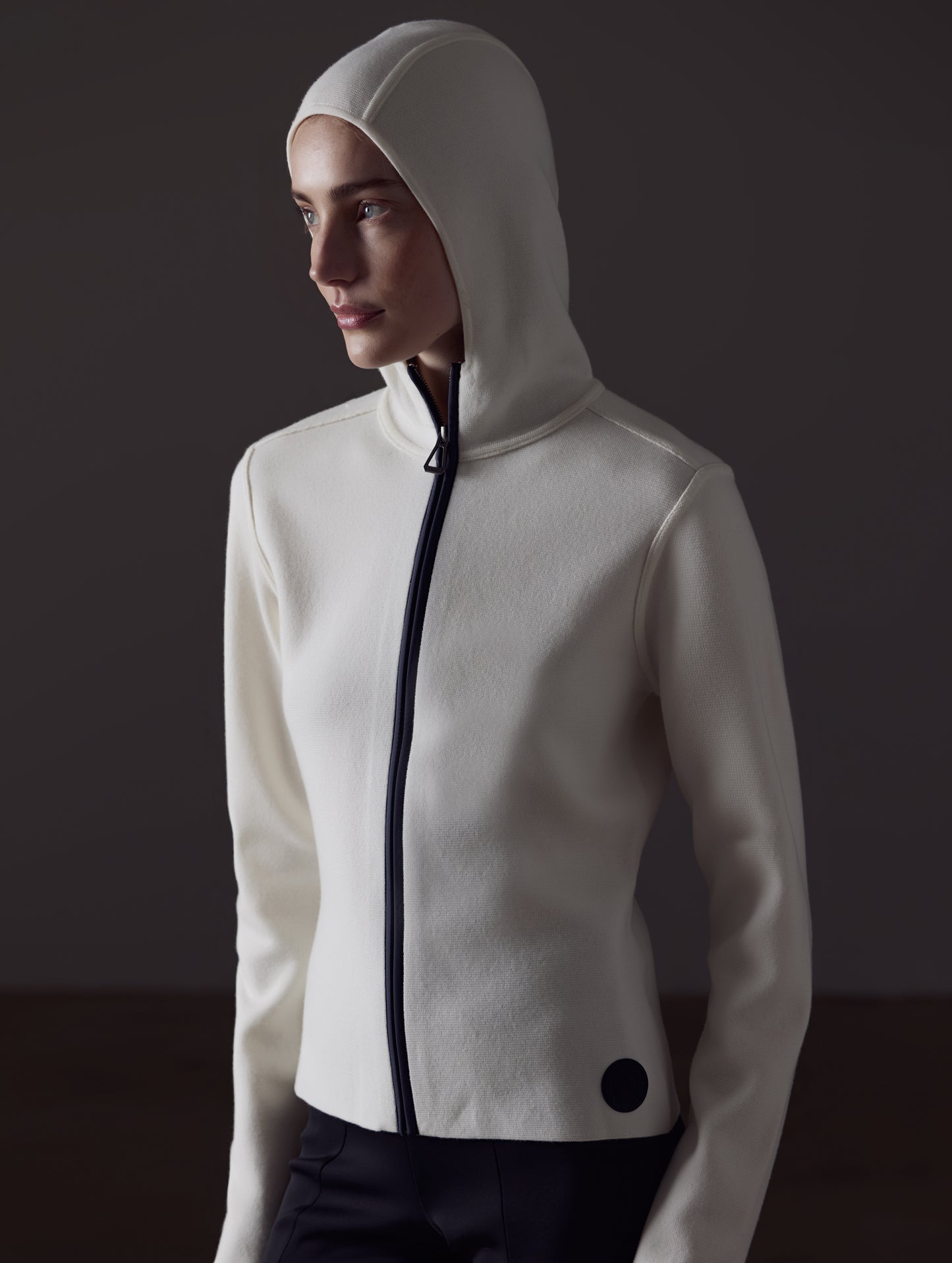 Front angled view of woman with hood up wearing Riley Full-Zip Sweater in Winter White from AETHER Apparel.