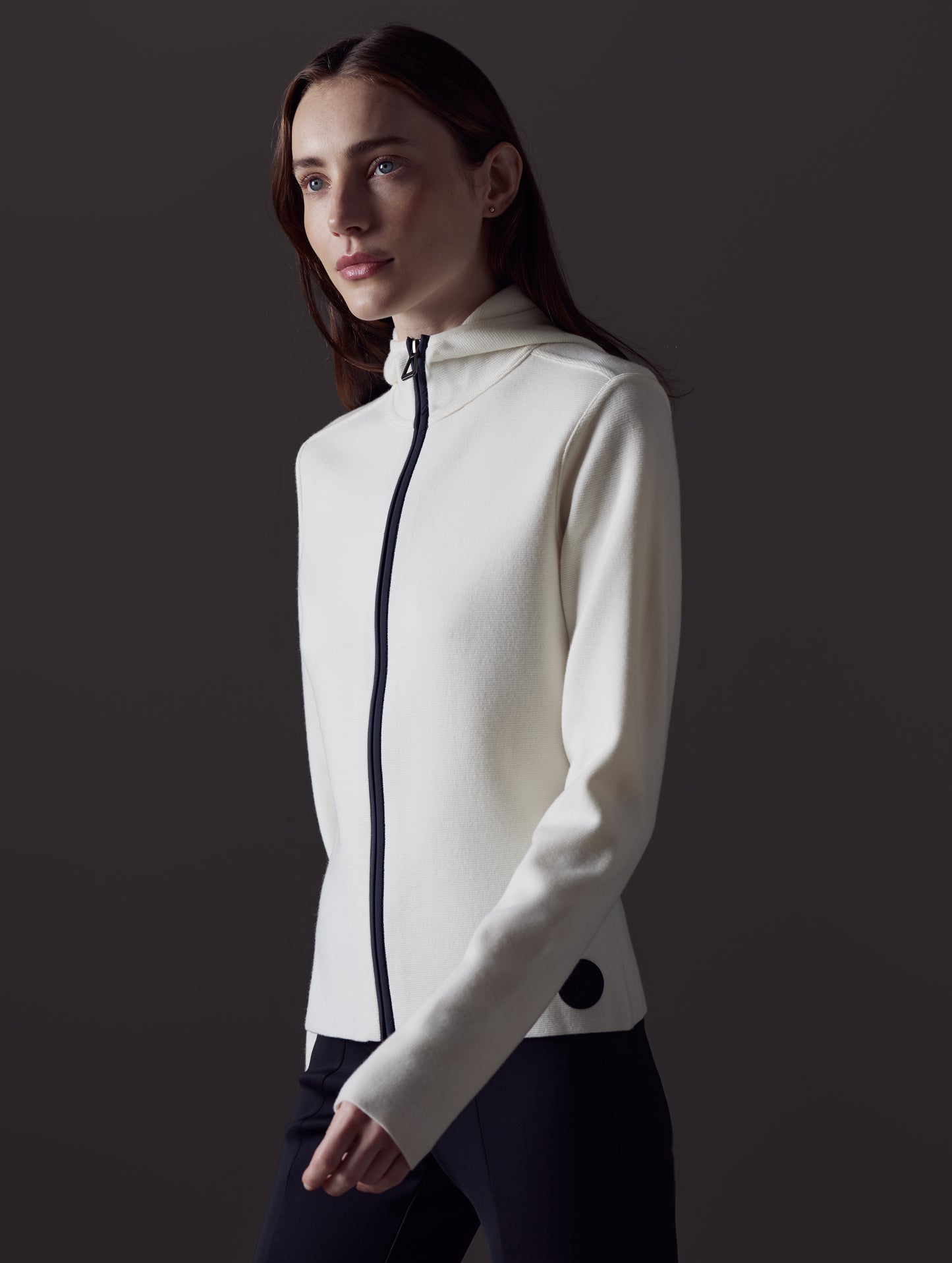 Front angled upper body view of woman walking wearing Riley Full-Zip Sweater in Winter White from AETHER Apparel.