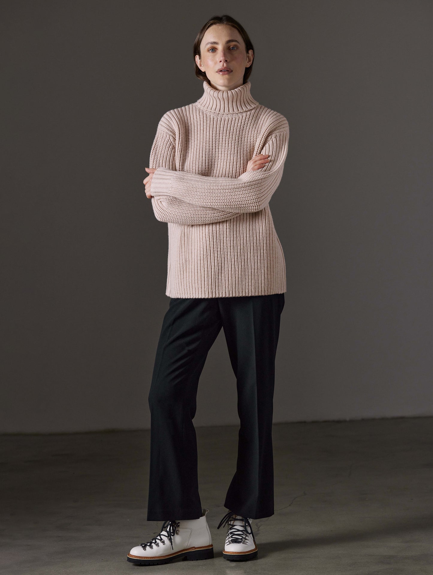 Front full-body view of woman wearing Sherwood Turtleneck Sweater in Blush beige from AETHER Apparel.