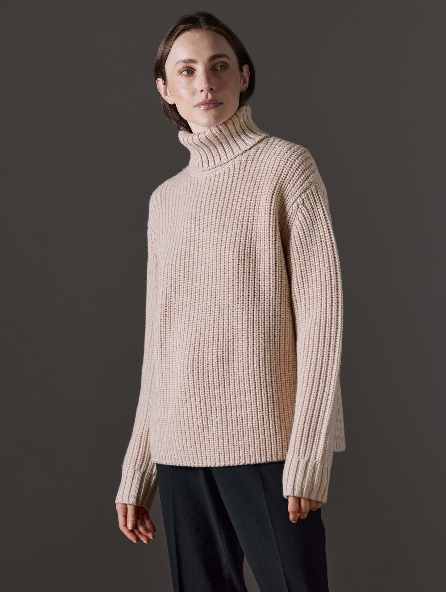 Front angled view of woman wearing Sherwood Turtleneck Sweater in Blush beige from AETHER Apparel.