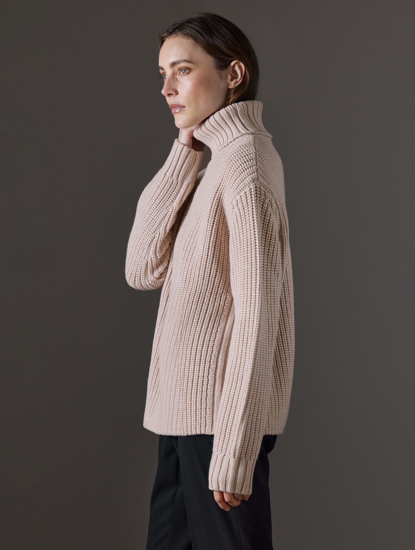 Side profile view of woman wearing Sherwood Turtleneck Sweater in Blush beige from AETHER Apparel.