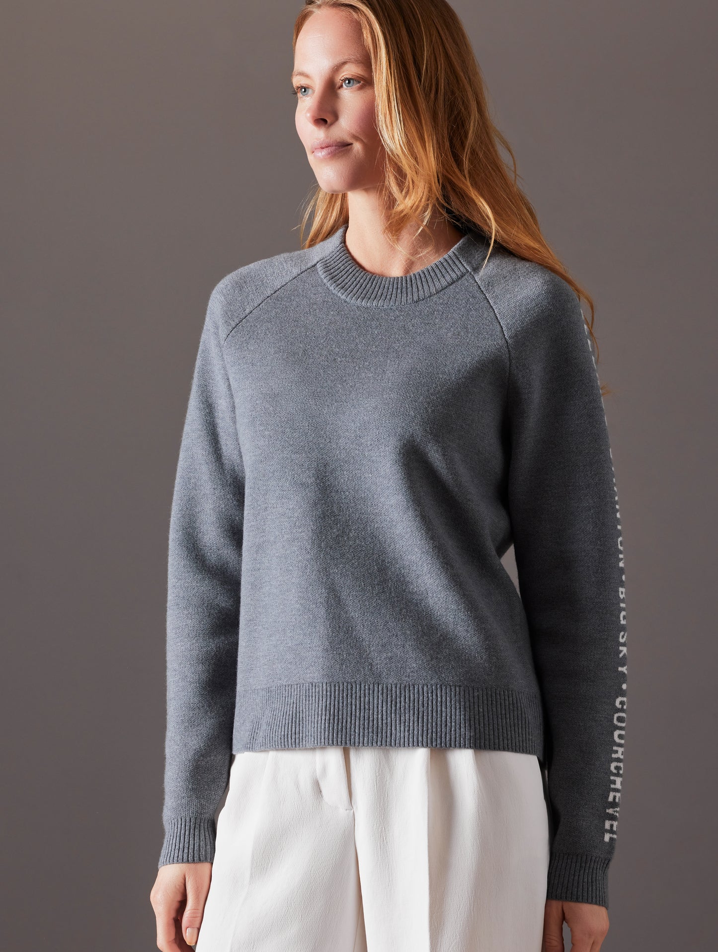 Front angled view of woman wearing Ski Town Sweater in Heather Grey from AETHER Apparel.