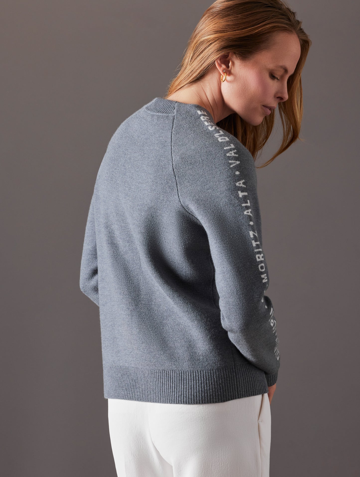 Rear angled view of woman wearing Ski Town Sweater in Heather Grey from AETHER Apparel.