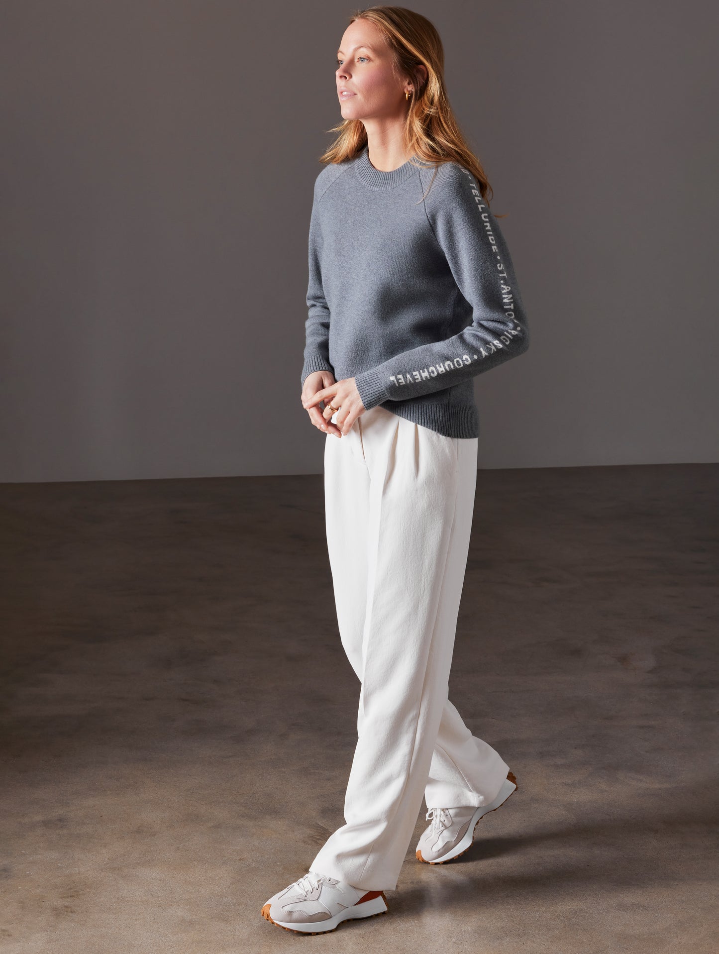 Front angled full-body view of woman wearing Ski Town Sweater in Heather Grey from AETHER Apparel.