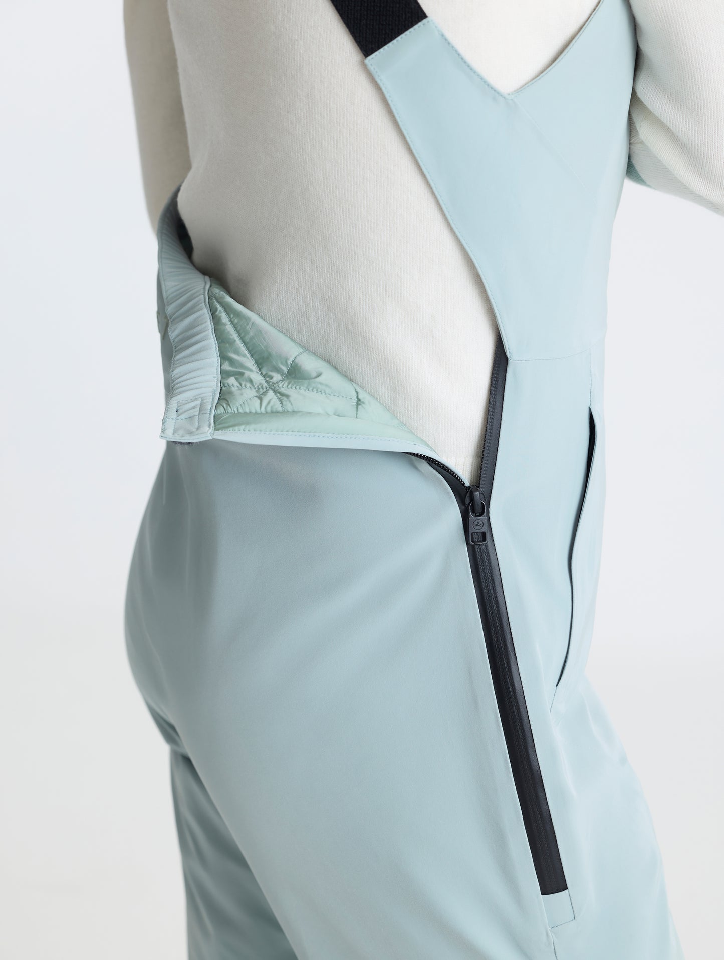 Closeup detailed view of the zipper-secured drop-seat on the Sophia Insulated Snow Bib in Jadewood Green from AETHER Apparel.
