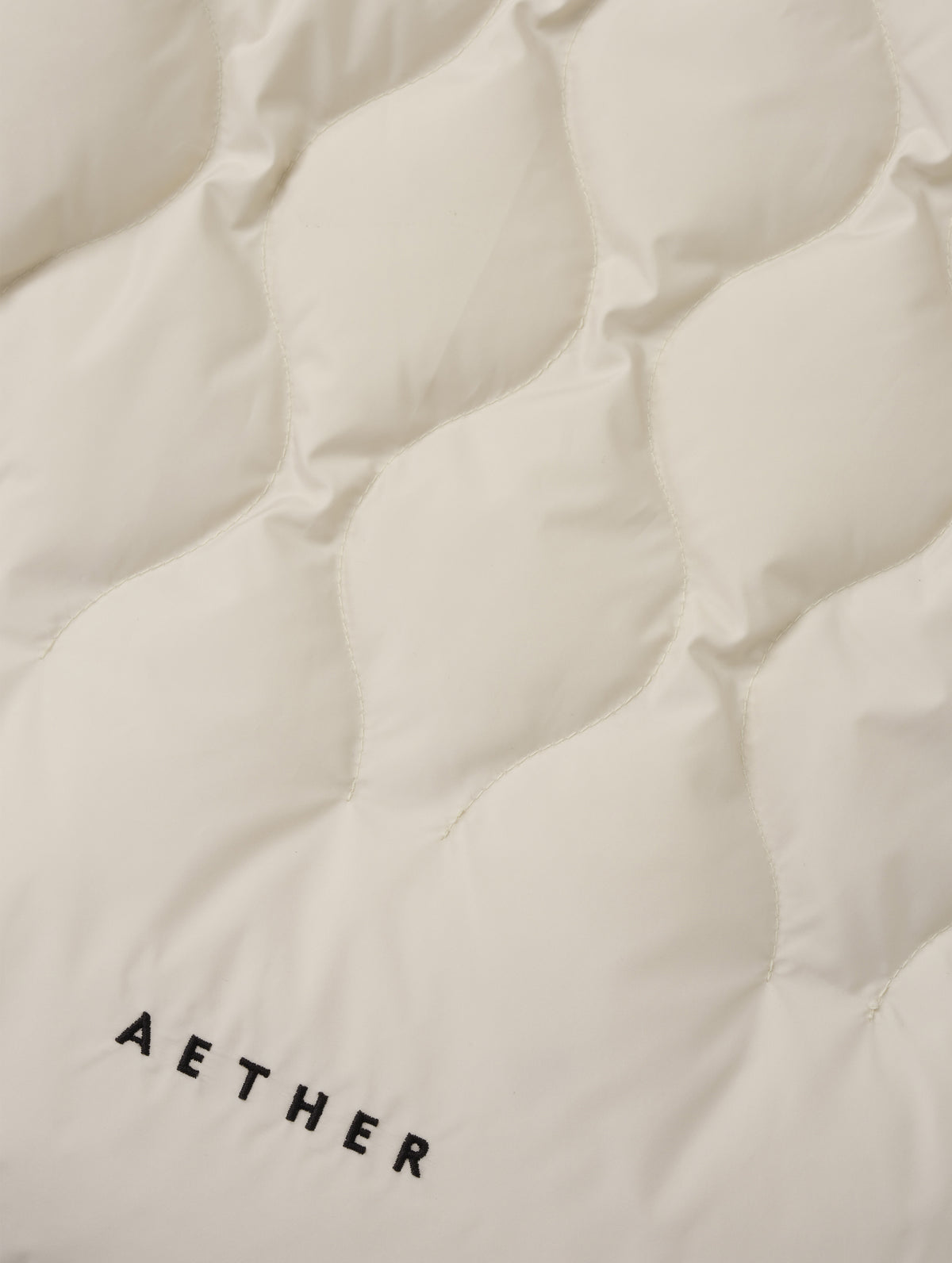 Closeup detailed view of the custom quilted pattern on the Stella Liner Jacket in Bone from AETHER Apparel with center-front closed.