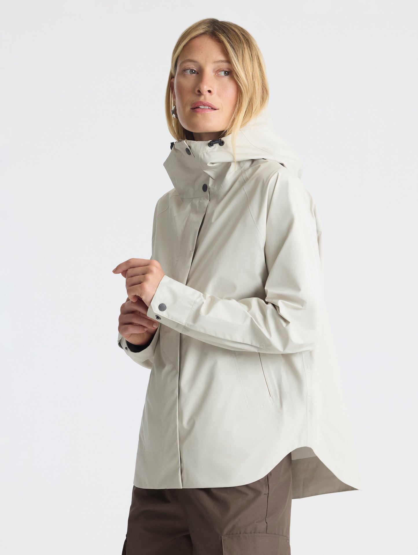 Left-angled view of woman wearing Storm All-Weather Jacket in Bone white from AETHER Apparel.