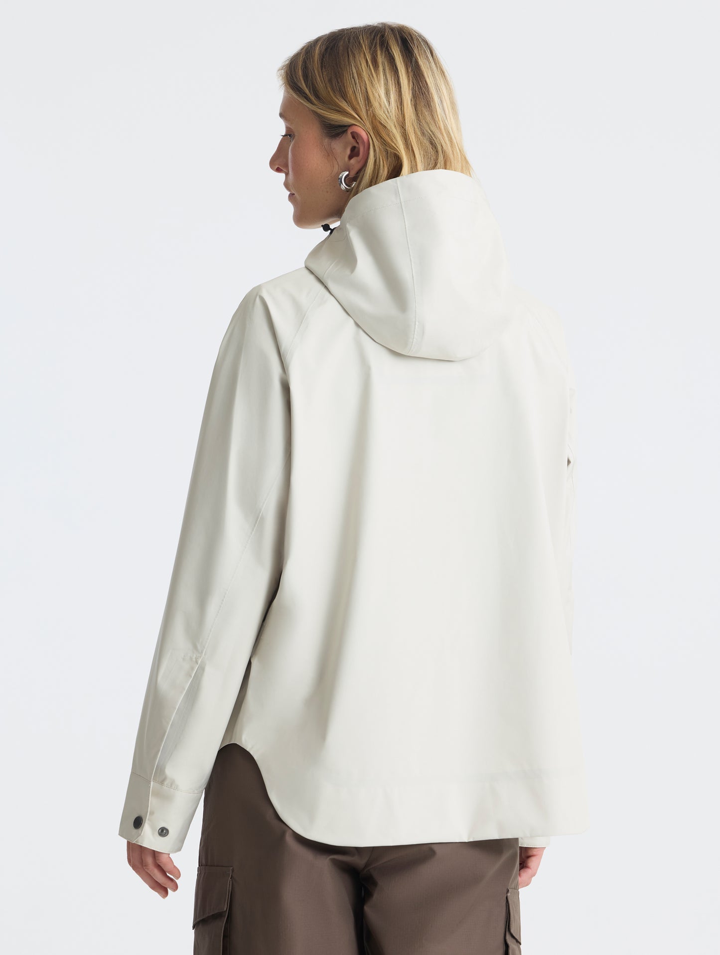 Rear view of woman wearing Storm All-Weather Jacket in Bone white from AETHER Apparel.