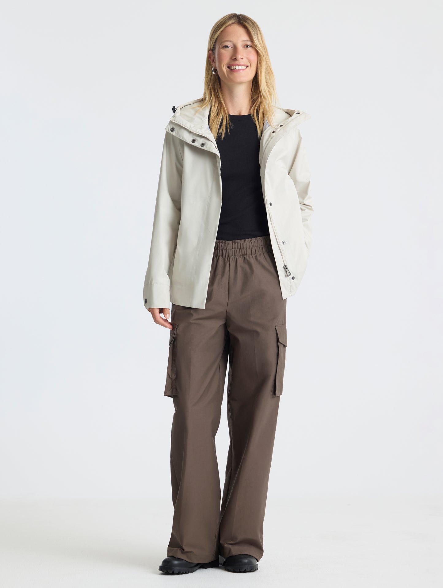 Full body view of woman wearing Storm All-Weather Jacket in Bone white from AETHER Apparel.