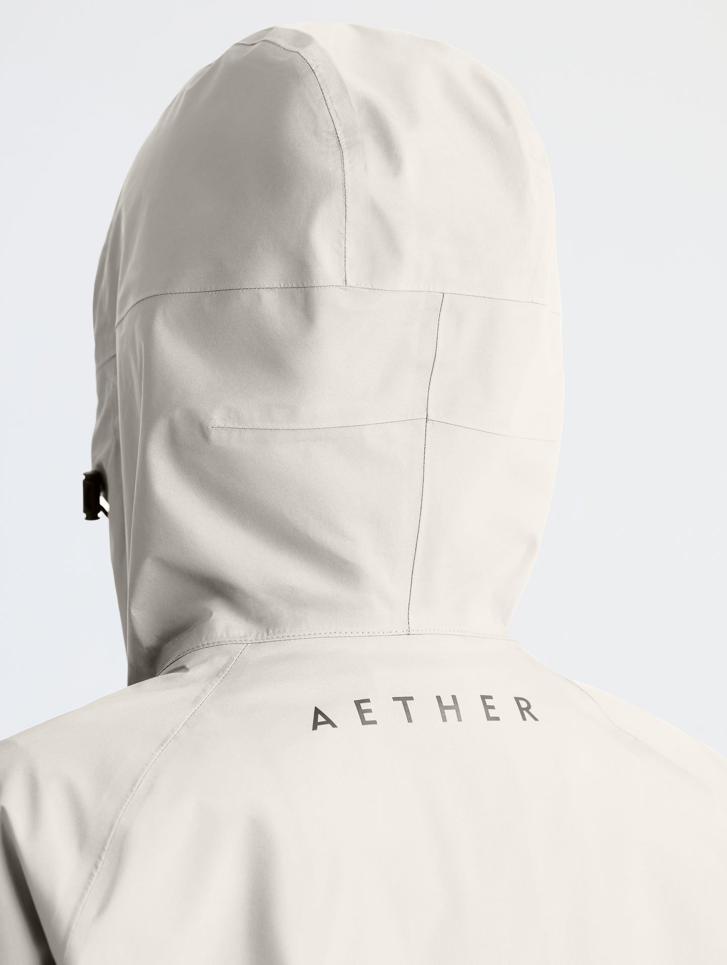 Rear closeup view of woman wearing hood of Storm All-Weather Jacket in Bone white from AETHER Apparel.