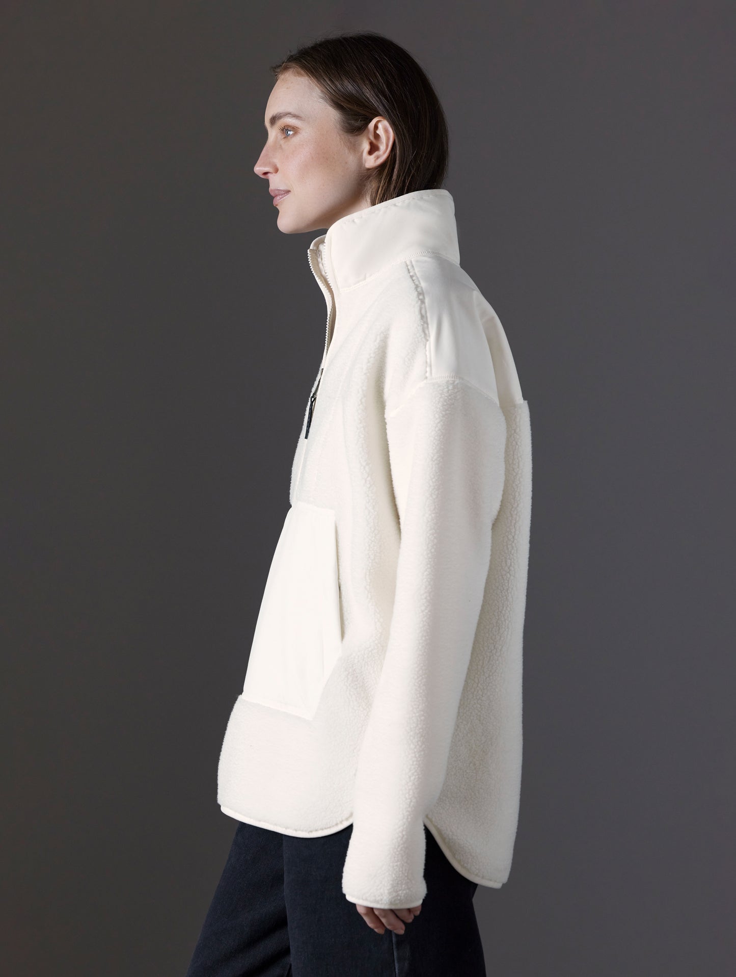 Side profile view of woman wearing Terrain Fleece Anorak in Winter White from AETHER Apparel.