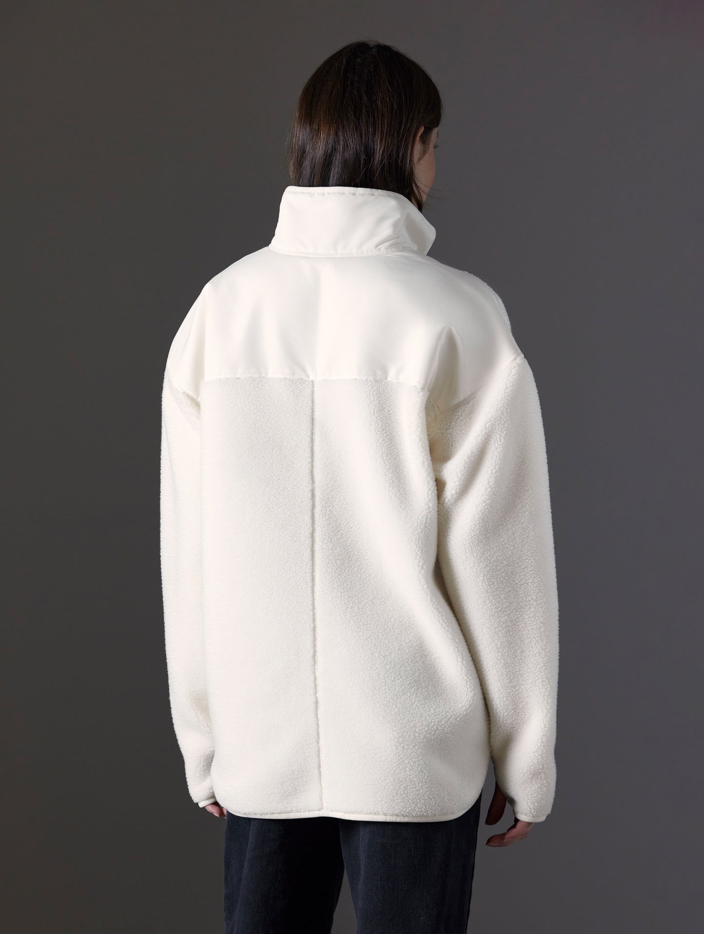 Rear angled view of woman wearing Terrain Fleece Anorak in Winter White from AETHER Apparel.