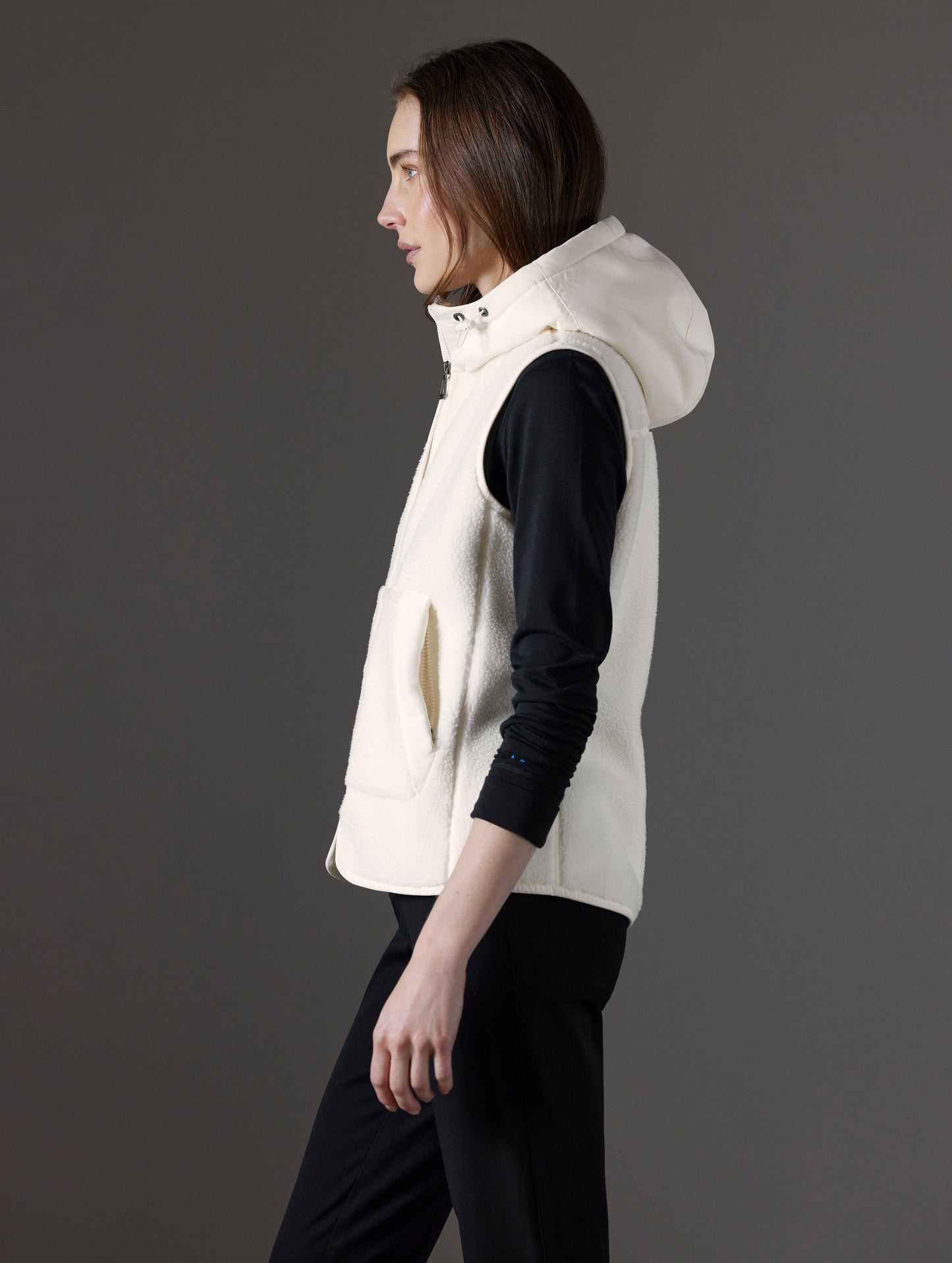 Side profile view of woman wearing Terrain Fleece Vest in Winter White from AETHER Apparel.