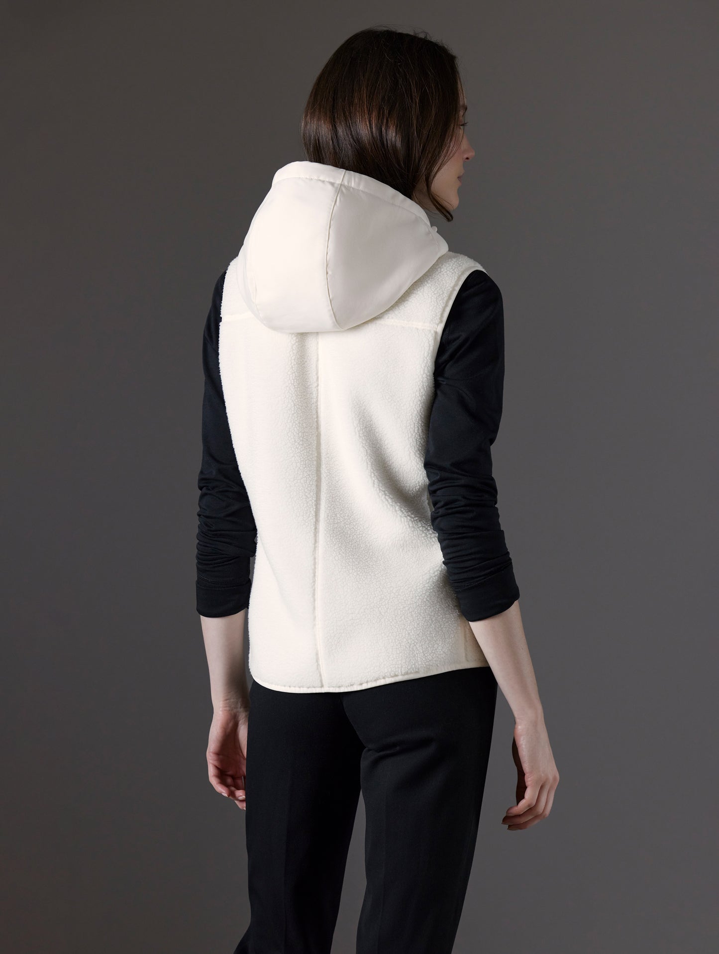 Rear angled view of woman wearing Terrain Fleece Vest in Winter White from AETHER Apparel.