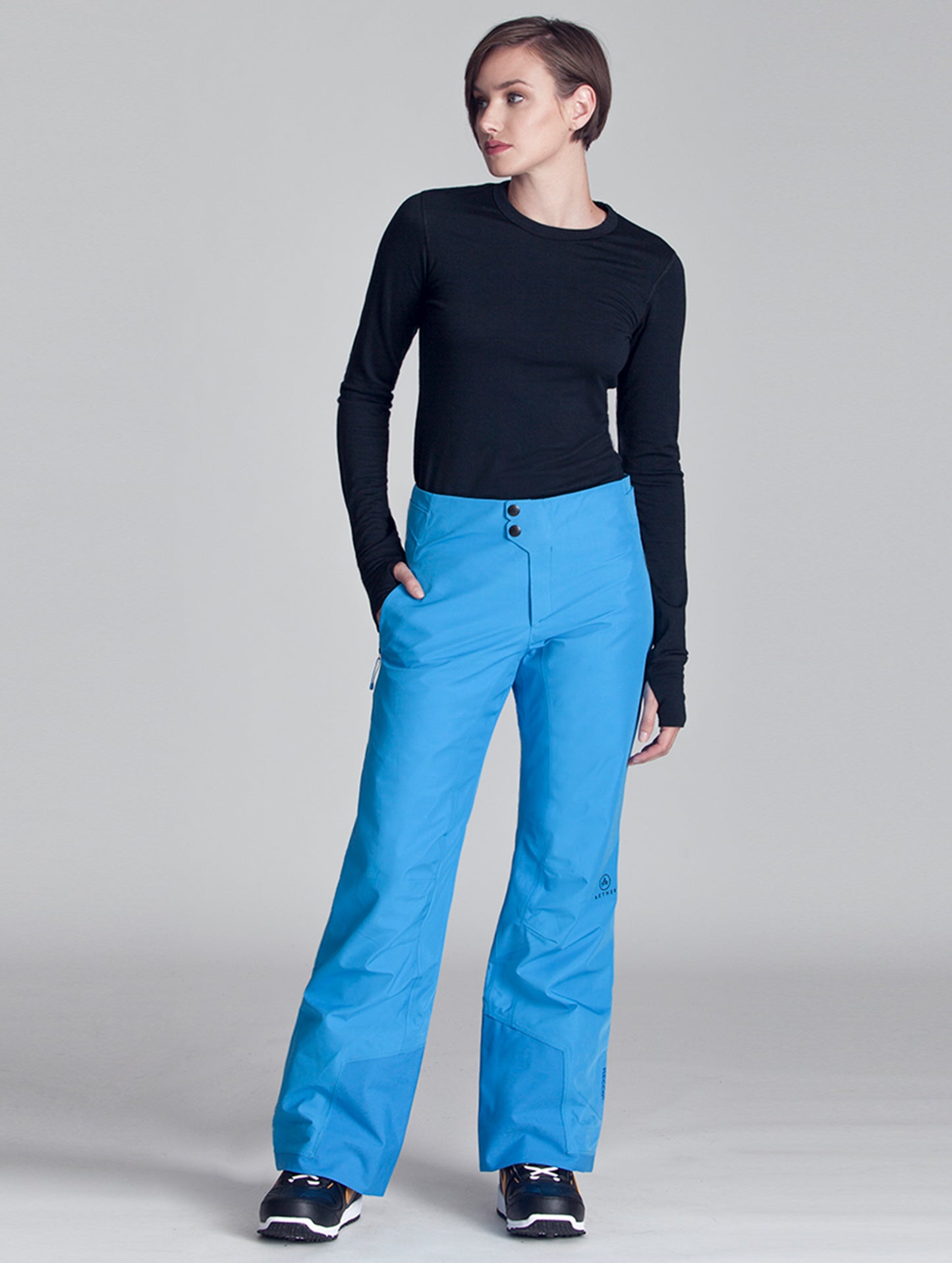 Full-body front view of woman wearing blue Vertex Snow Pant from AETHER Apparel.