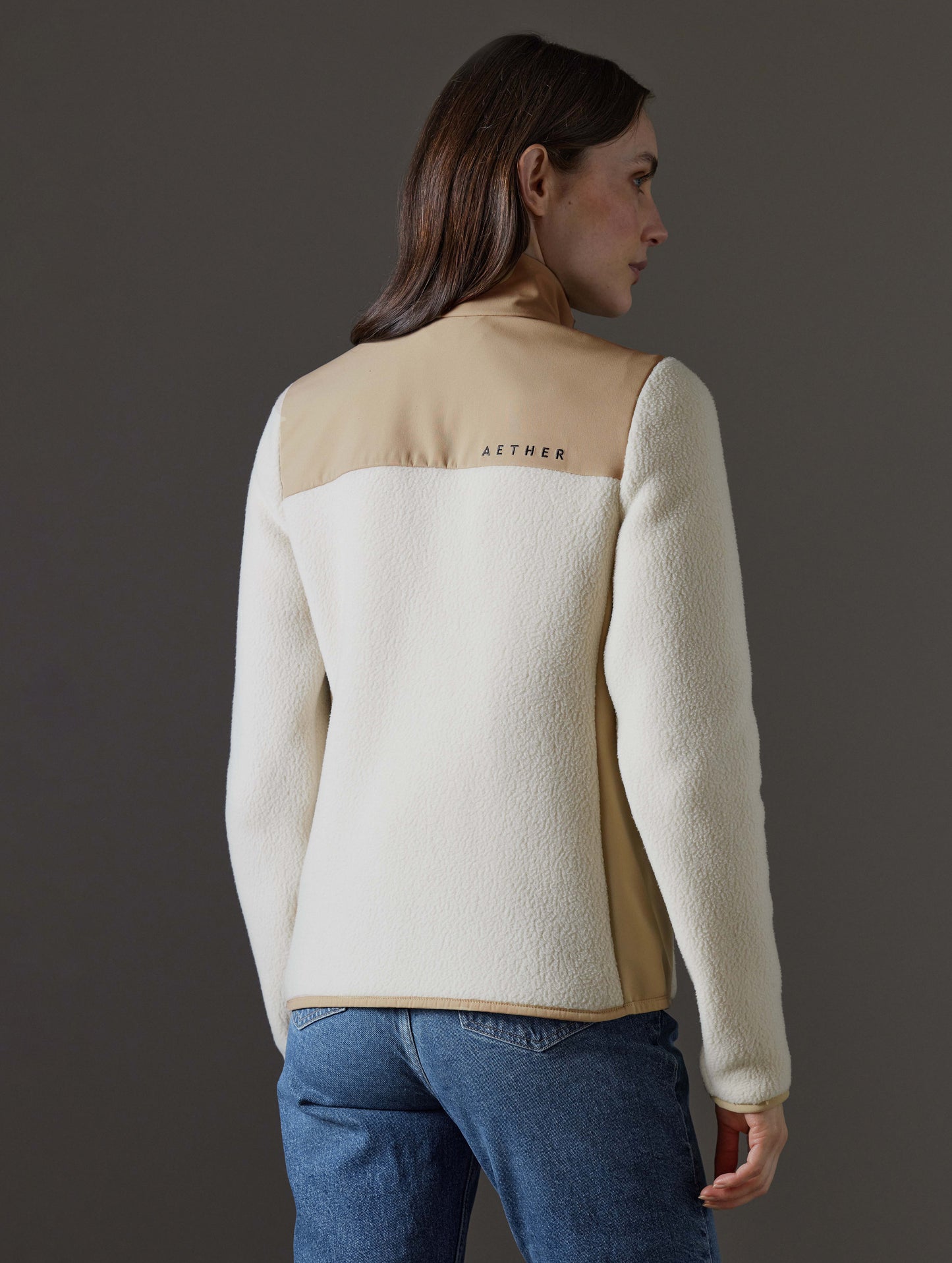 Rear angled body view of woman wearing Walsh Full-Zip 2.0 in Bone and Desert Tan from AETHER Apparel.