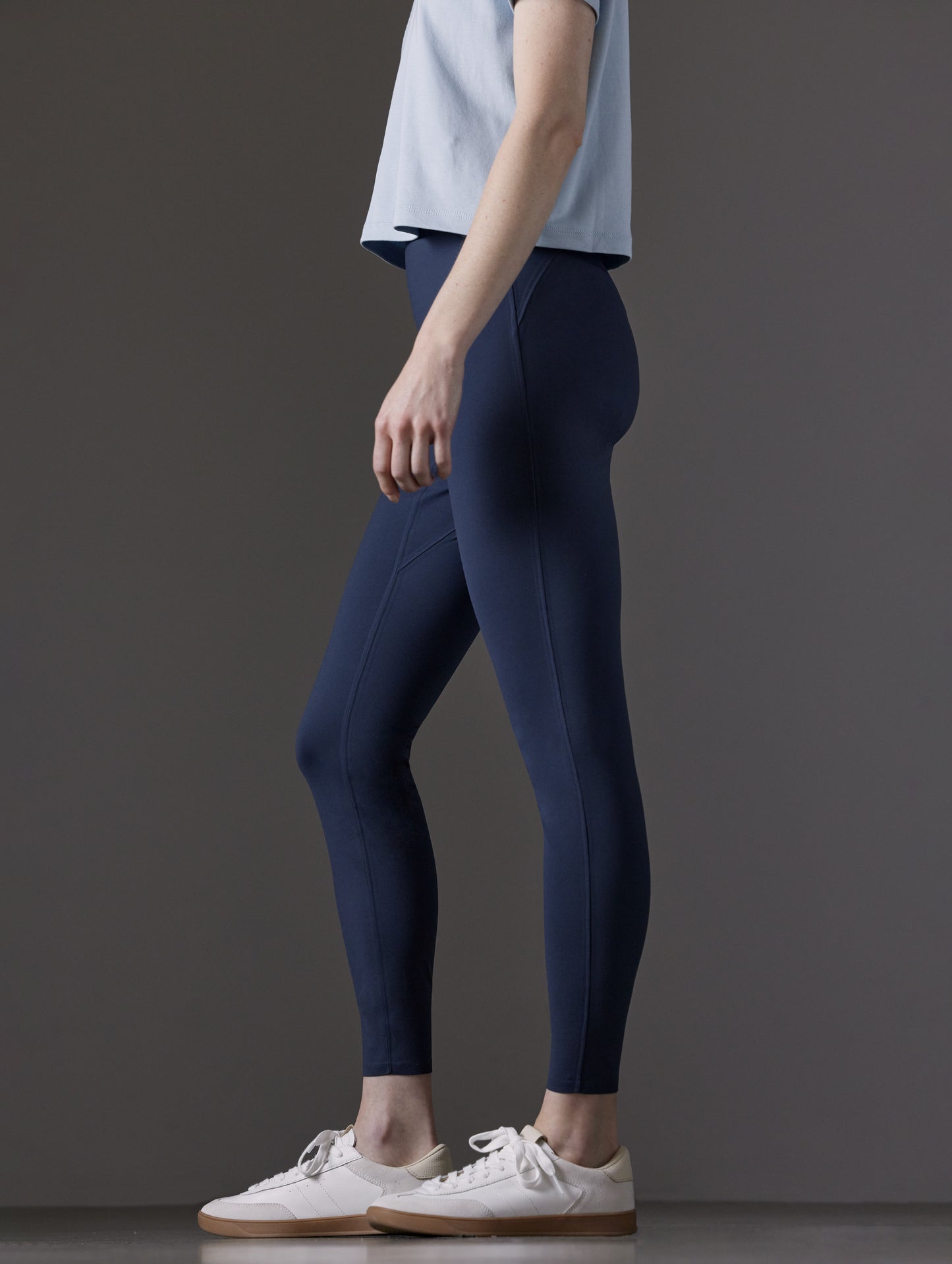Side profile lower body view of woman wearing Winter Legging 2.0 in Nordic Navy blue from AETHER Apparel.