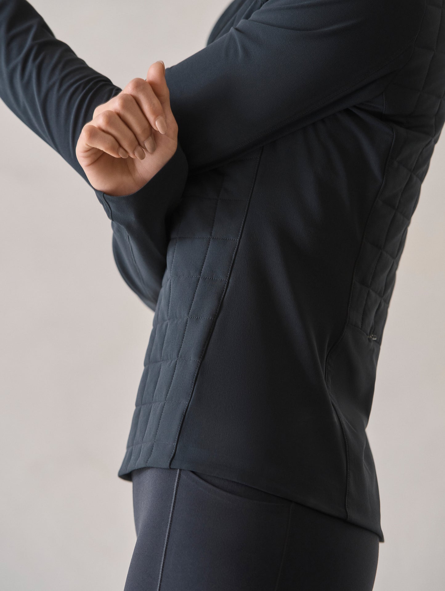Closeup view of woman with crossed arms wearing the Wren Insulated Half-Zip in Onyx Black from AETHER Apparel.