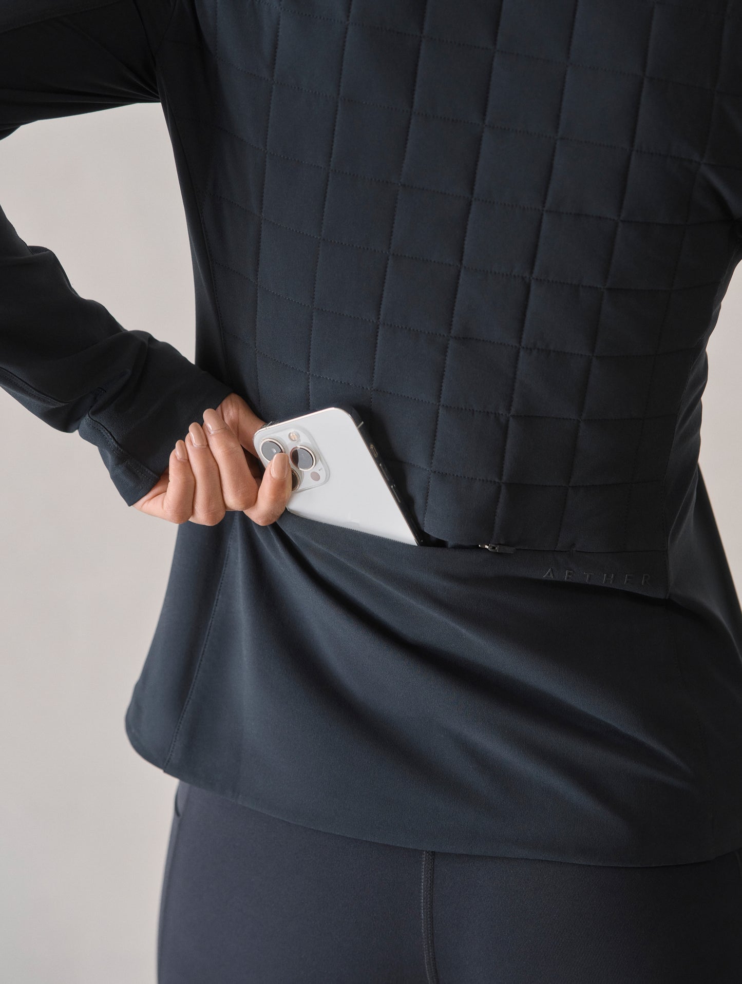 Closeup detailed view of the hidden zippered back pocket on the Wren Insulated Half-Zip in Onyx Black from AETHER Apparel.