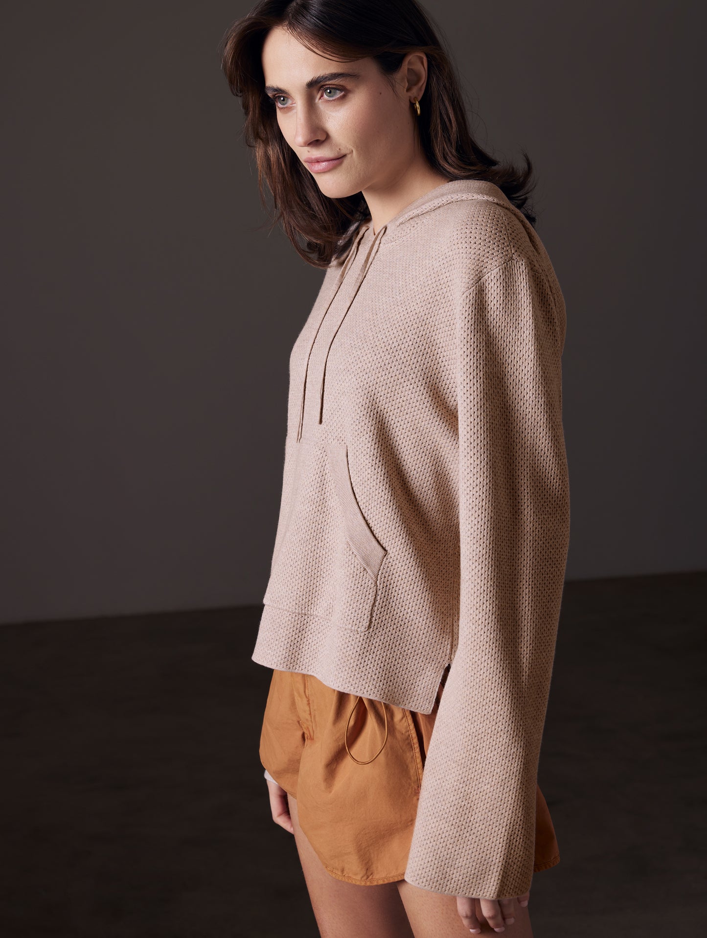 Front angled view of woman wearing Baja Mesh Sweater in Desert Beige from AETHER Apparel.