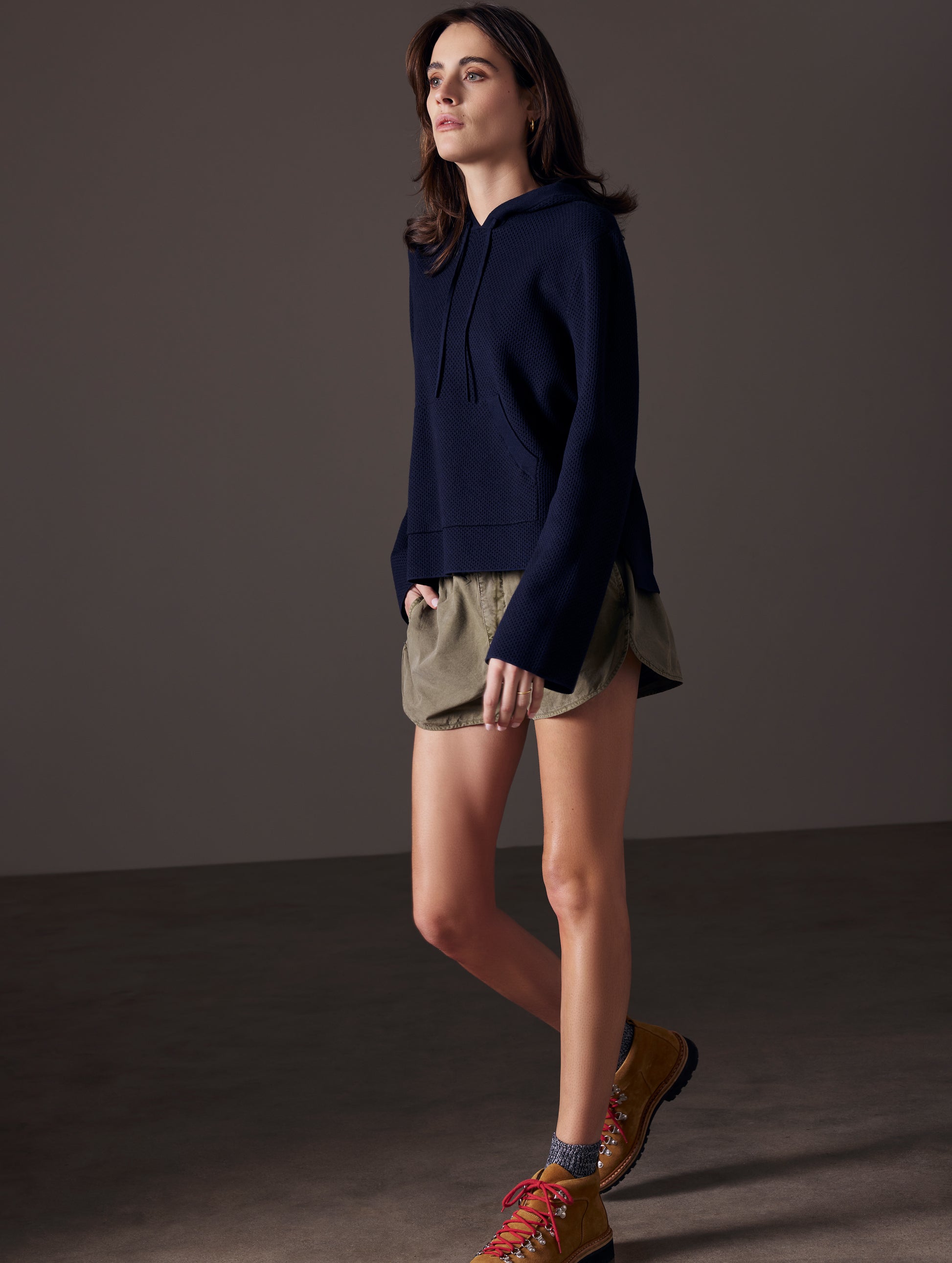 Front angled full-body view of woman wearing Baja Mesh Sweater in Total Eclipse dark blue from AETHER Apparel.